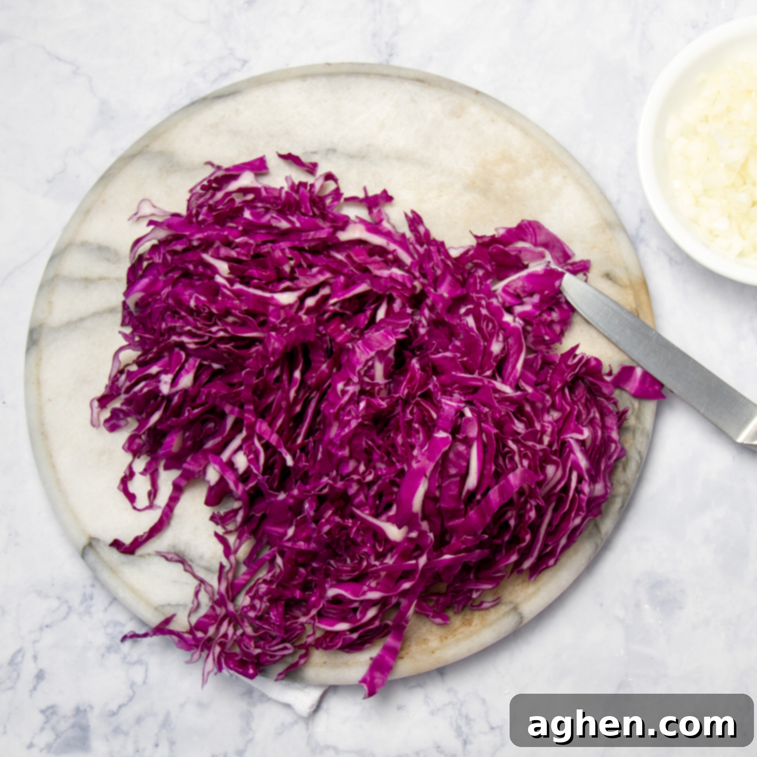 Slow Cooker Tangy Red Cabbage 4 Finely shredded red cabbage on a round cutting board.