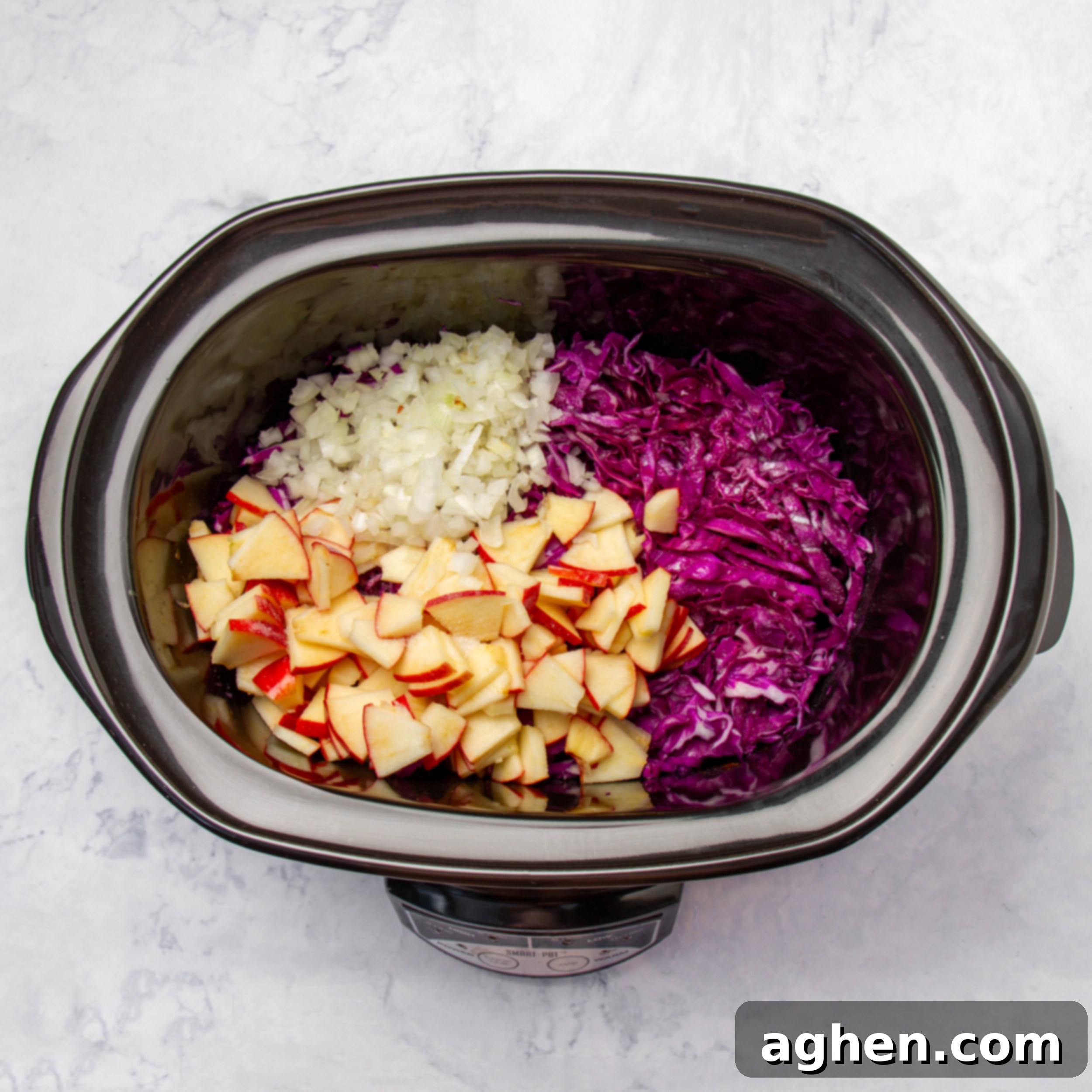 Slow Cooker Tangy Red Cabbage 6 Apples, onion, and cabbage in the slow cooker ready to be mixed and cooked.