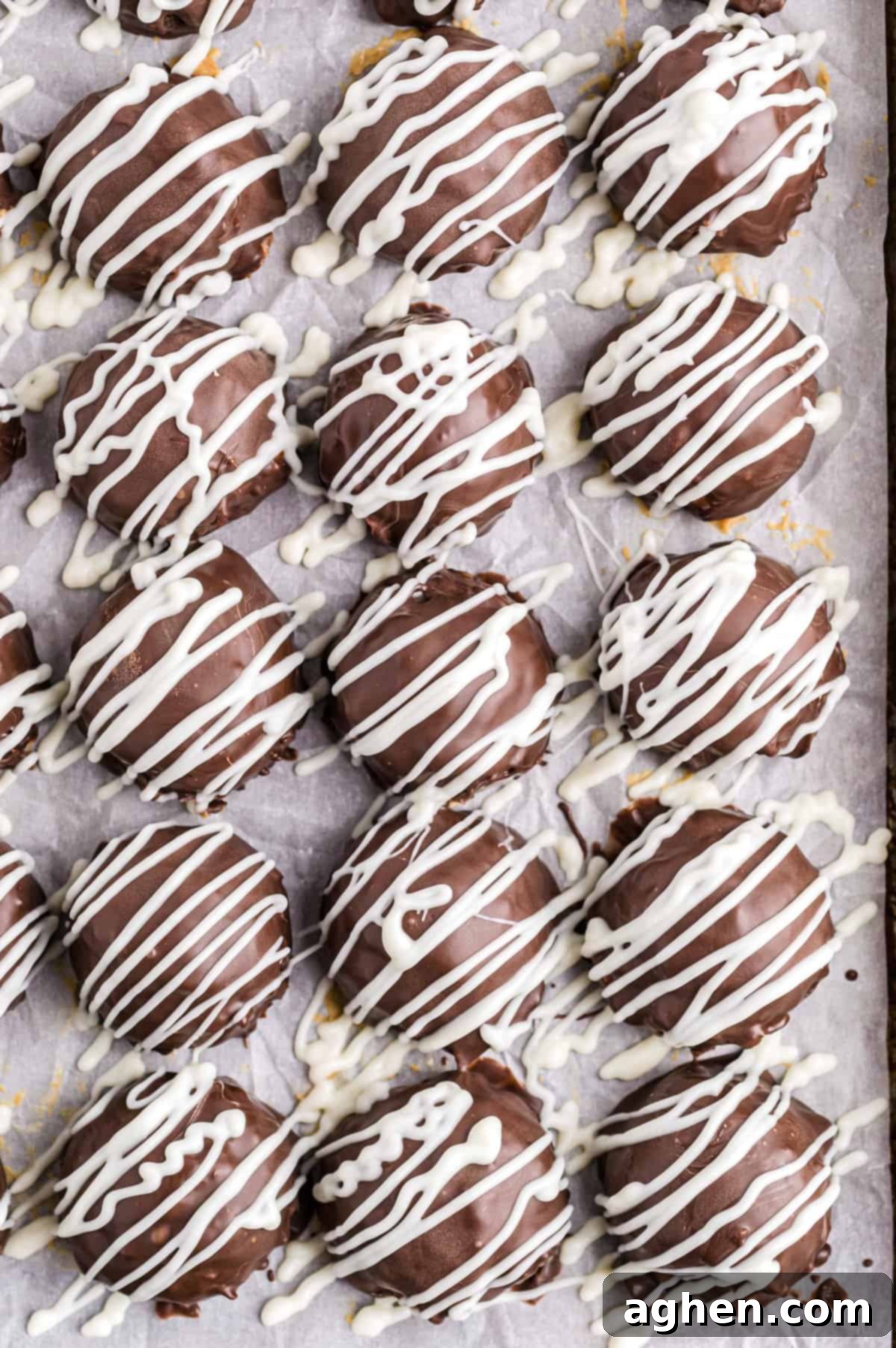 No-Bake Peanut Butter Crunch Bites 8 Rice Krispie Buckeyes drizzled with White Chocolate on a baking sheet, ready to set.