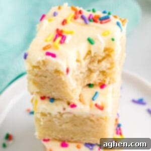 Tender Frosted Sugar Cookie Bars 12 frosted sugar cookie bars stacked on top of each other, with a bite taken out of the top one