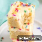 Tender Frosted Sugar Cookie Bars 25 frosted sugar cookie bars stacked on top of each other, with a bite taken out of the top one