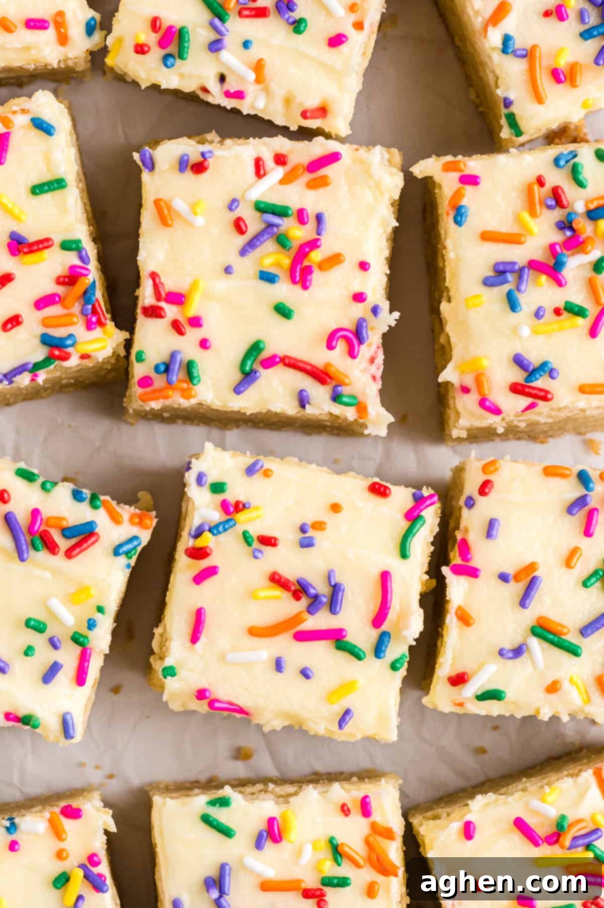 Tender Frosted Sugar Cookie Bars 3 A top-down view of a pan of freshly baked and frosted sugar cookie bars, generously adorned with rainbow sprinkles and neatly sliced into perfect squares, ready for serving.
