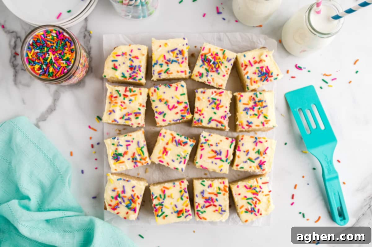Tender Frosted Sugar Cookie Bars 9 Sugar cookie bars, baked in an 8x8 inch pan, fully frosted with white icing and topped with colorful sprinkles, cut into neat squares and ready for serving.