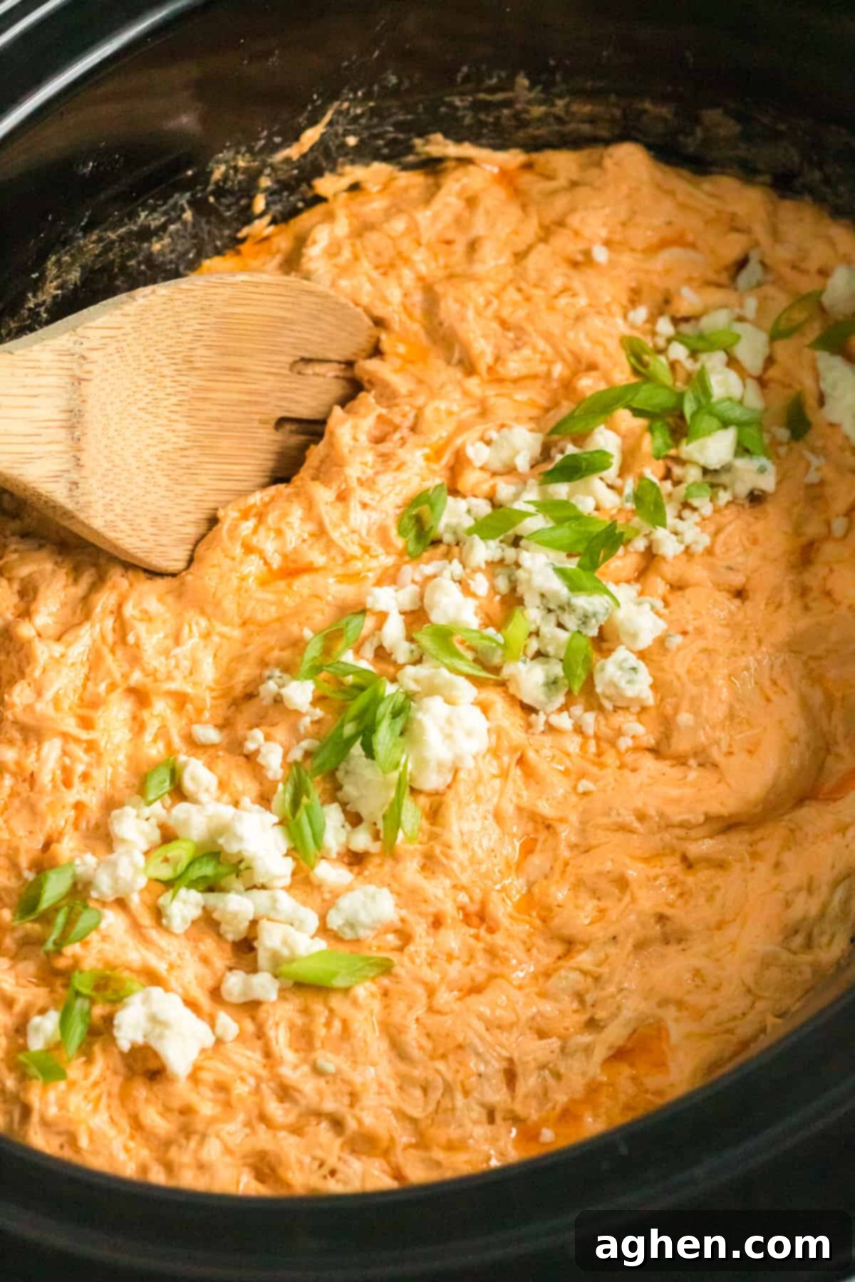 Crockpot buffalo chicken dip with blue cheese and green onions on top.