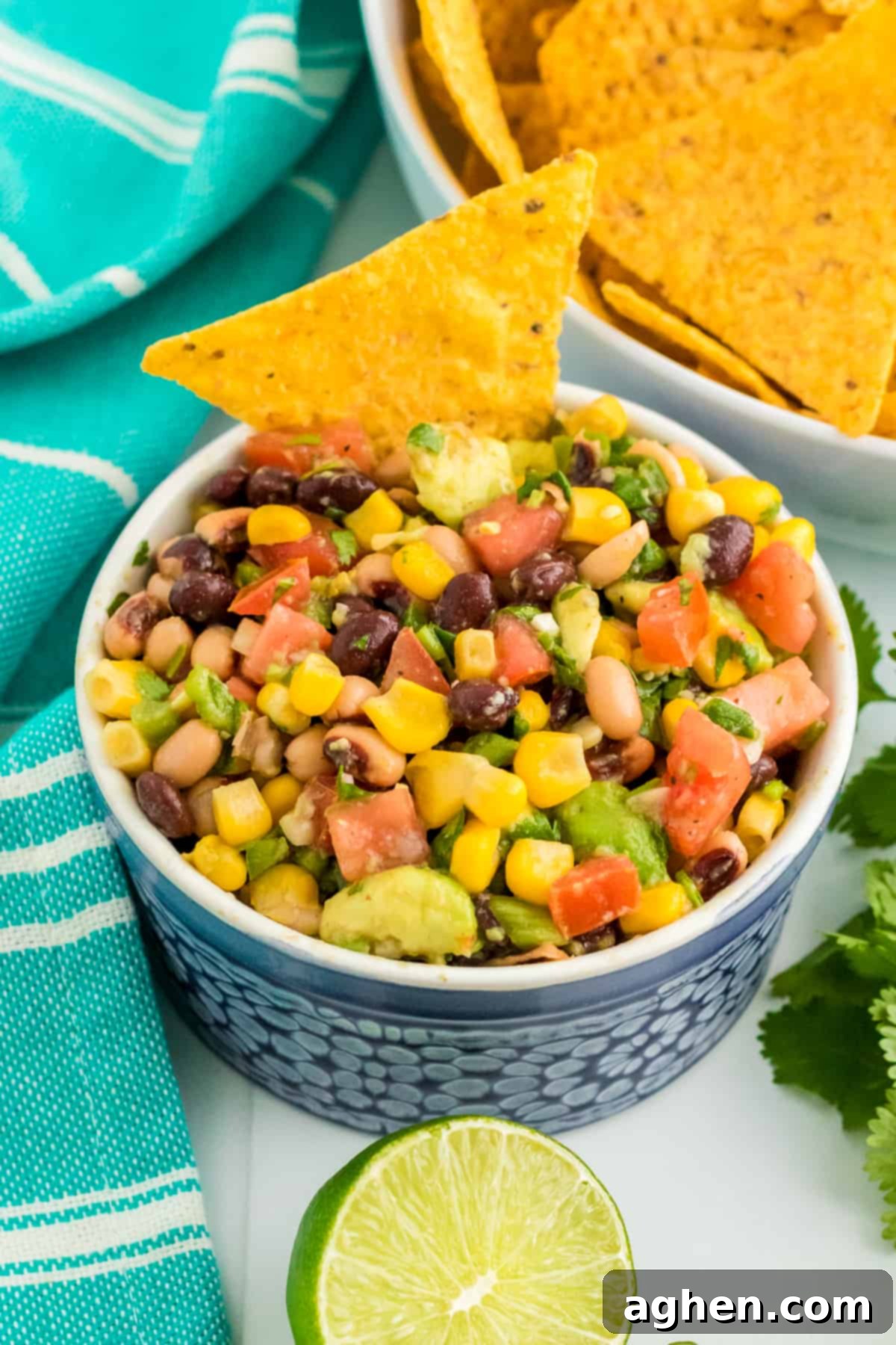 Cowboy Caviar dip with beans, avocado, corn, tomatoes, scallions, and dressing in a bowl, served with tortilla chips