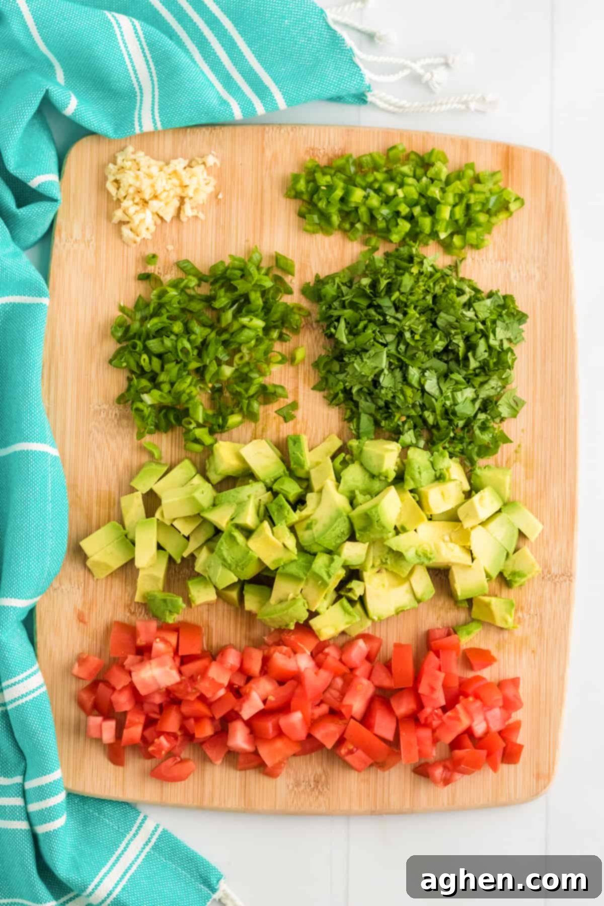 Chopped garlic, scallions, jalapeno, cilantro, avocado, and tomato on a cutting board, ready for Cowboy Caviar.