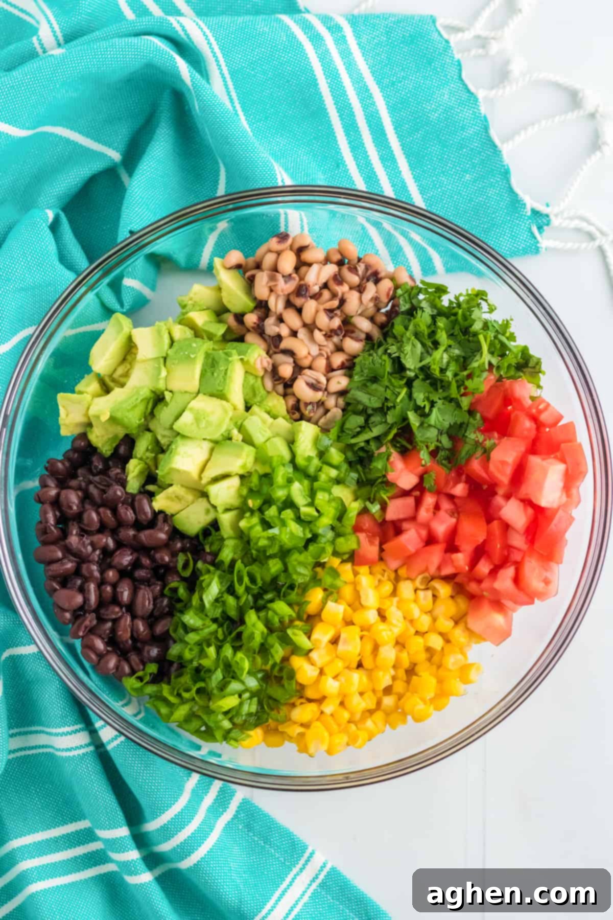Corn, black beans, black-eyed peas, and chopped avocado, jalapeño, scallions, tomatoes, and cilantro in a large mixing bowl, ready for the dressing.