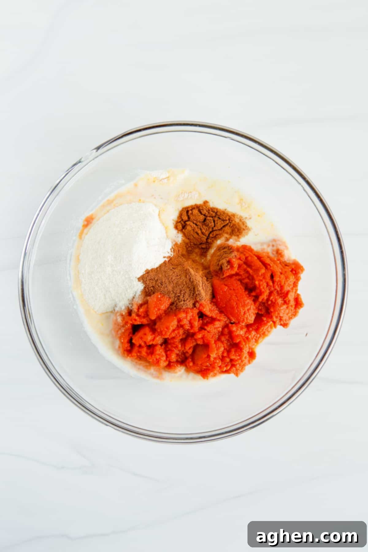 milk, pudding mix, pumpkin puree, and pumpkin spice in a glass mixing bowl