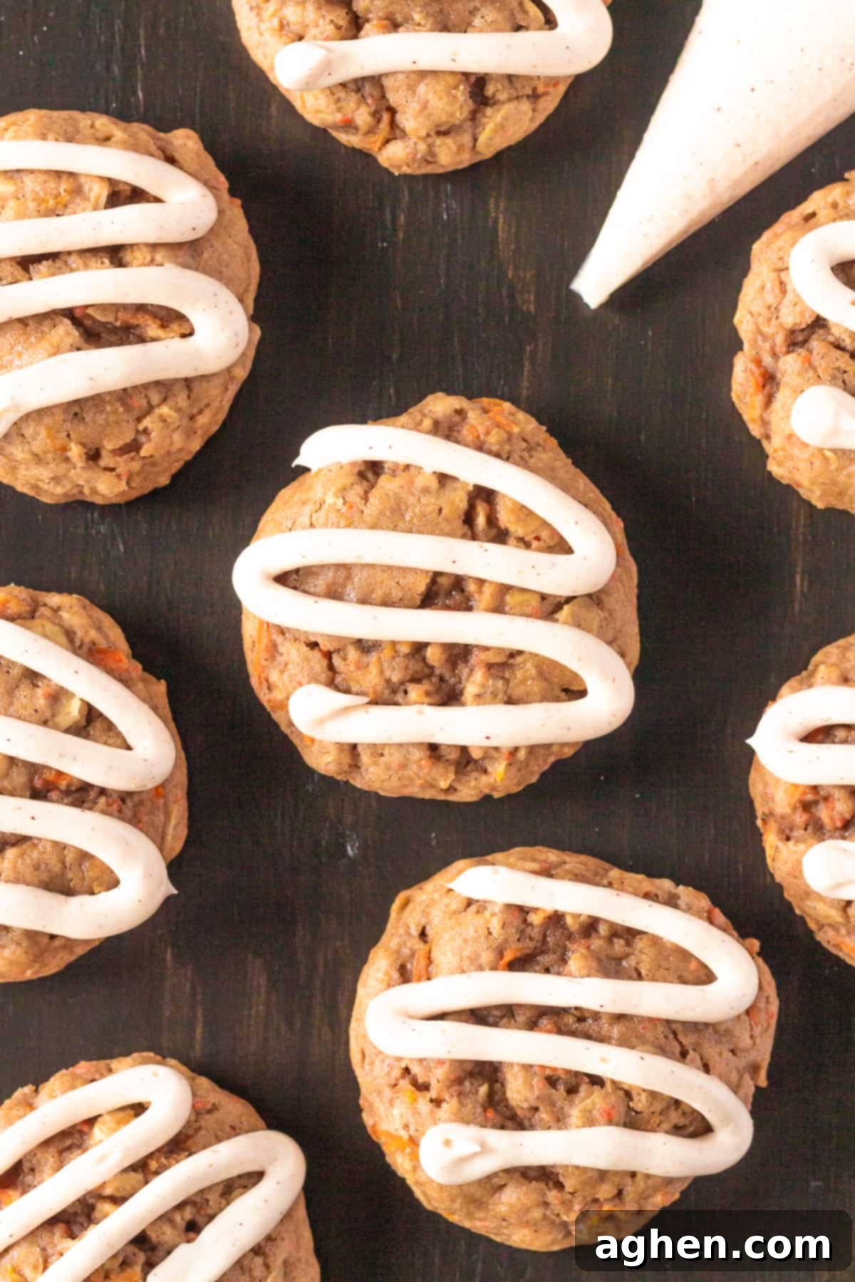 Finished carrot cake mix cookies beautifully frosted with cream cheese icing, with a piping bag beside them, ready for serving.