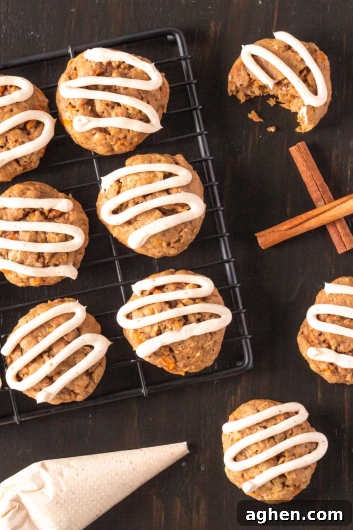 Frosted Carrot Cake Cookies arranged on a cooling rack, with a piping bag, cinnamon sticks, and additional cookies on the side, creating a cozy and inviting scene.