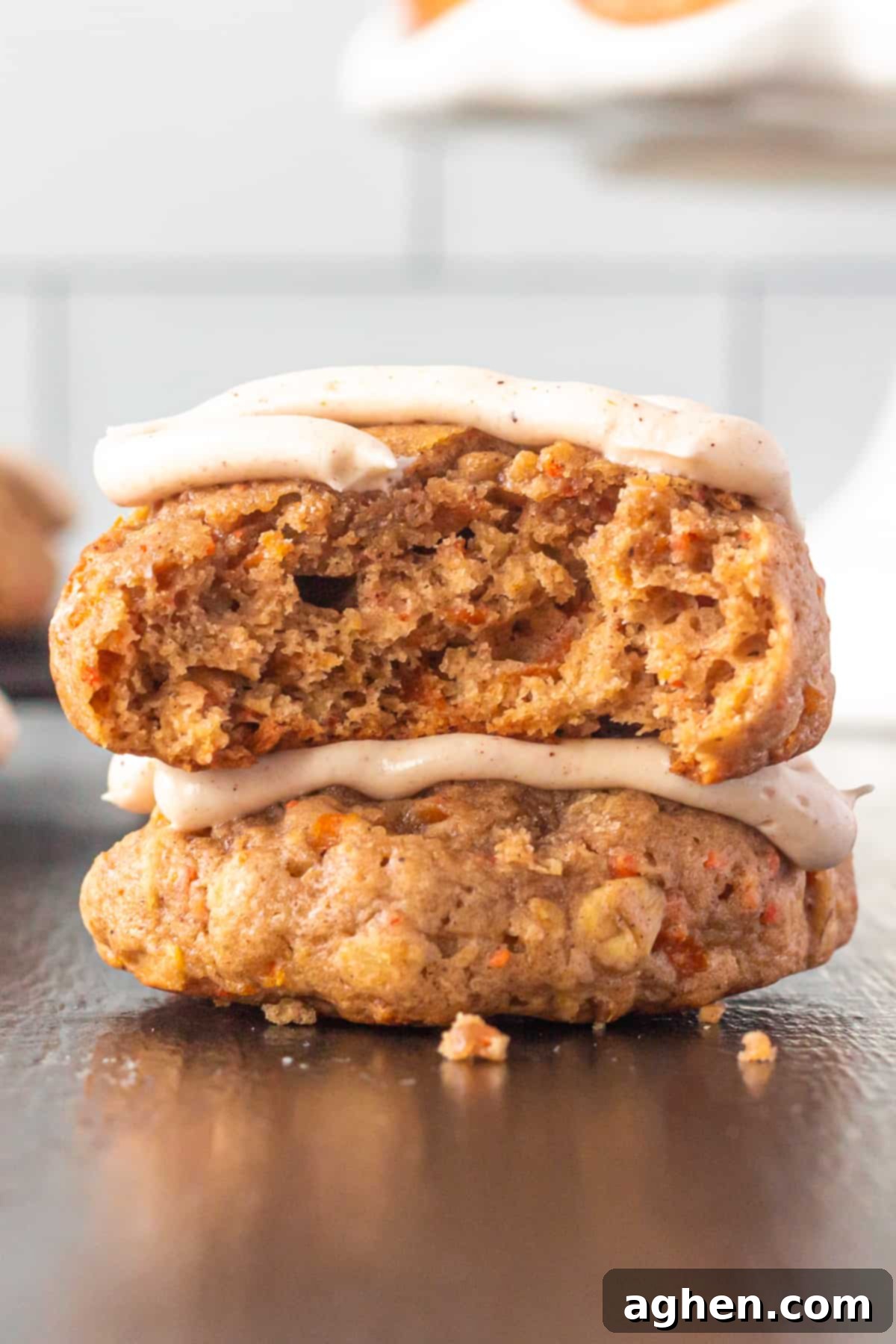 A close-up of a thick and chewy carrot cake cookie with a small bite taken out, revealing its moist, cake-like interior and delightful texture.