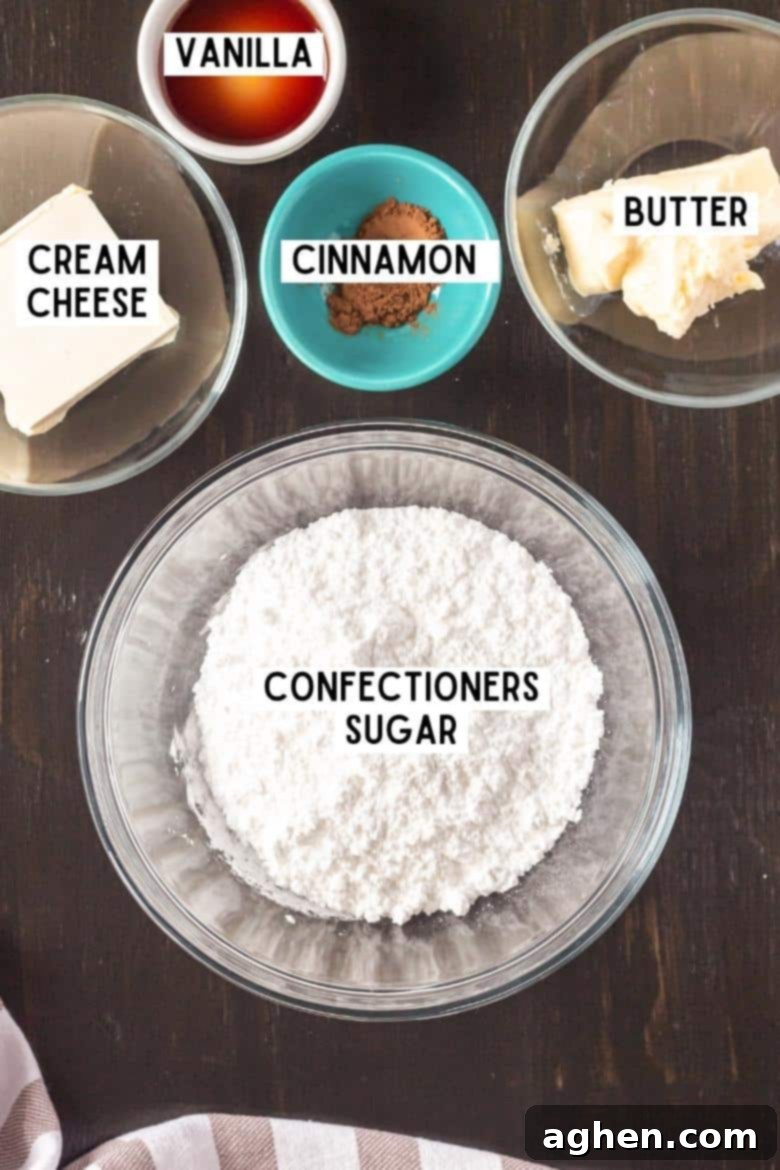 Ingredients for homemade cream cheese frosting laid out: confectioners' sugar, unsalted butter, ground cinnamon, cream cheese, and vanilla extract.