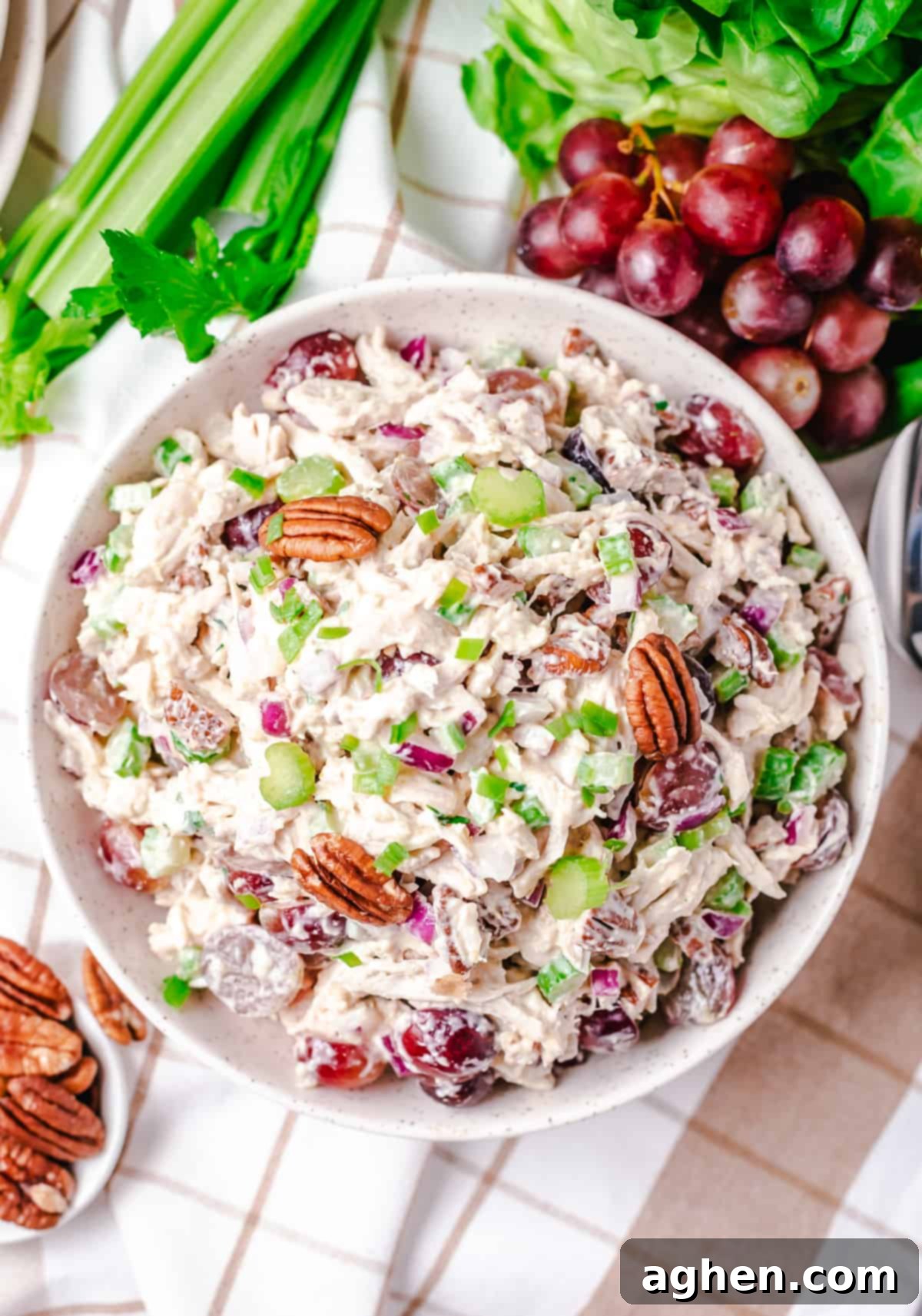 Large white bowl of chicken salad with grapes, pecans, and celery.