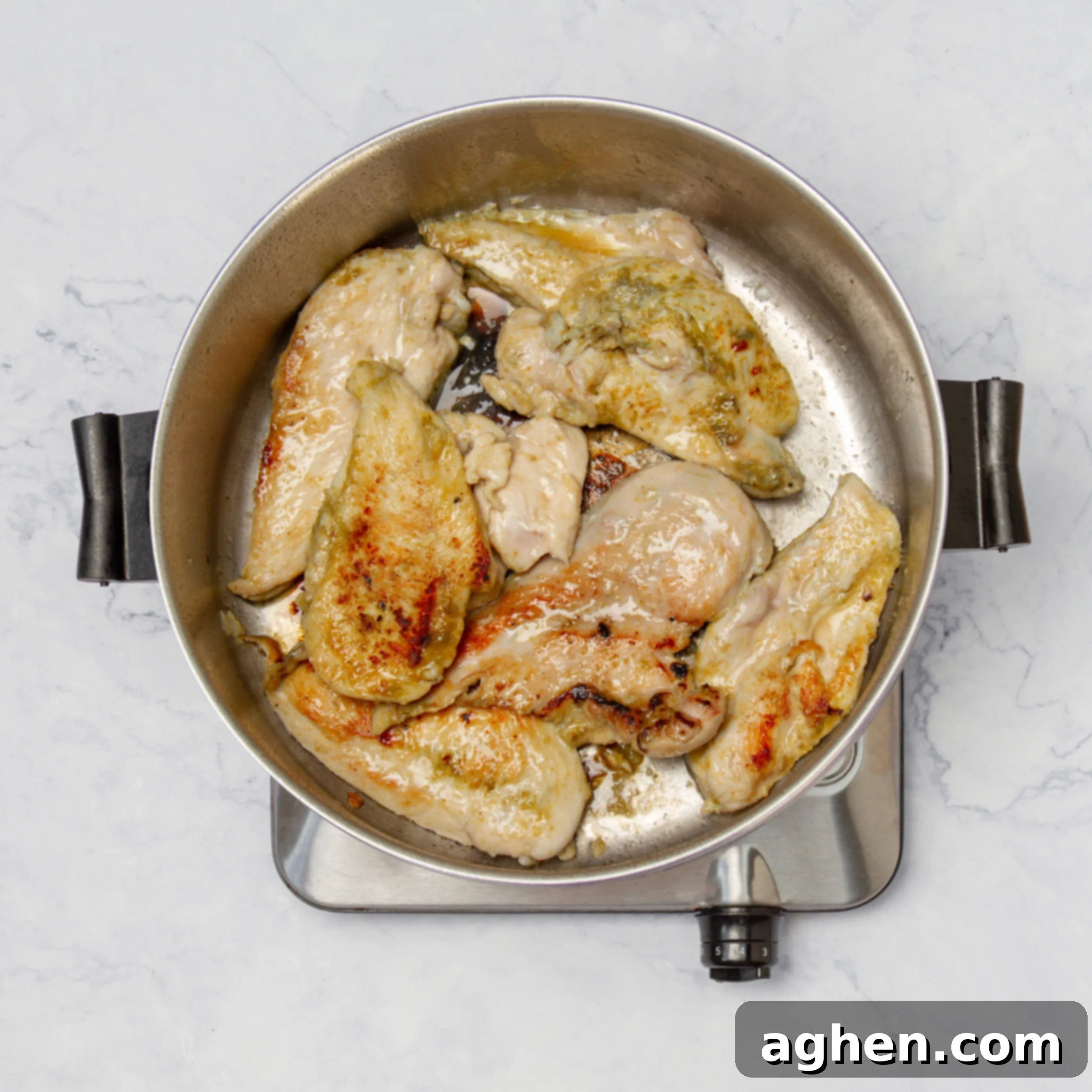 Seasoned chicken breasts expertly searing in a hot pan, developing a beautiful golden-brown crust. The sizzle and slight browning indicate the crucial step of building flavor before the chicken is fully cooked in the sauce.