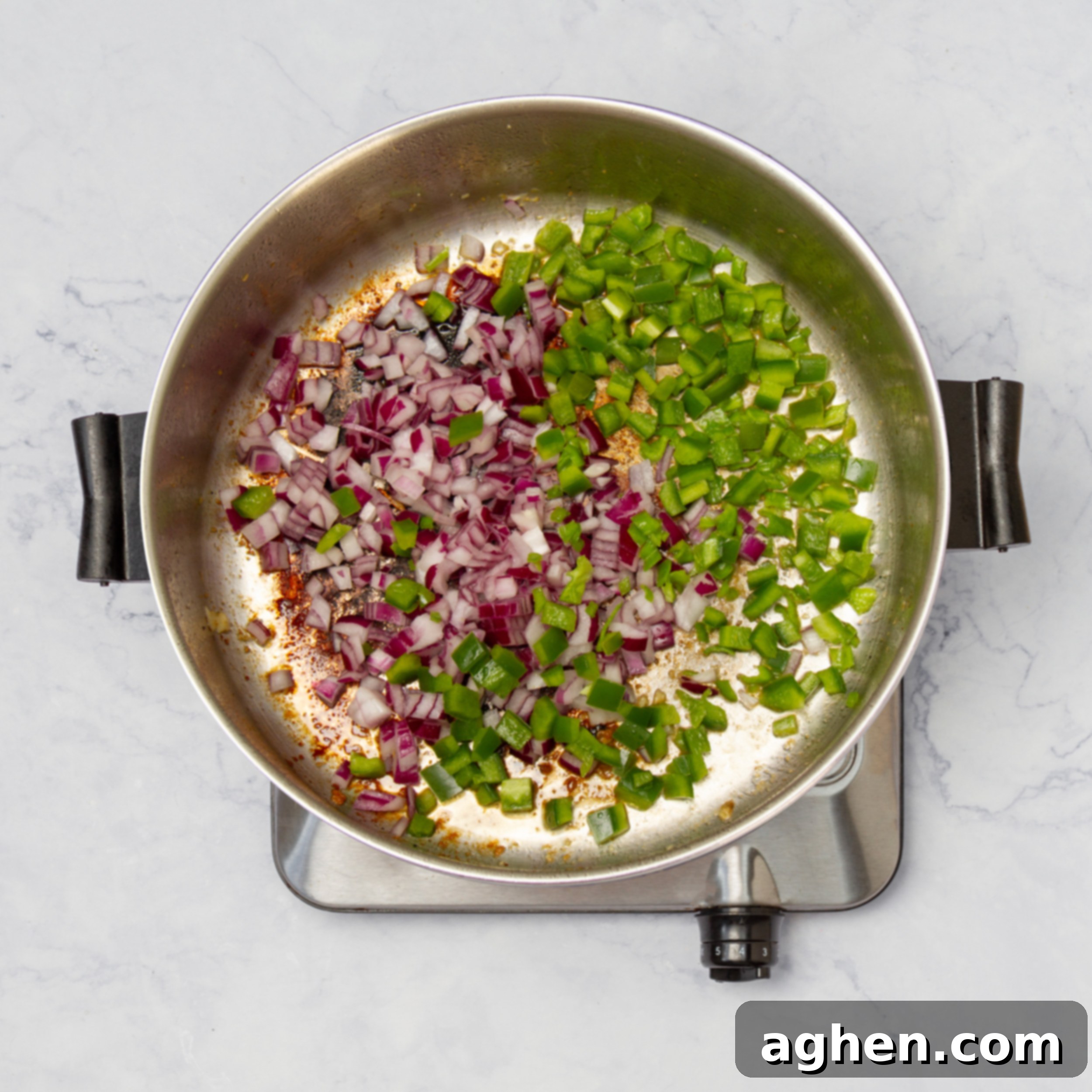 The 'Holy Trinity' of Creole cooking – chopped red onions, green bell peppers, and celery – along with green chilis, expertly sautéing in a pan. The vegetables are softening and becoming translucent, building the aromatic base for the Chicken Creole sauce.