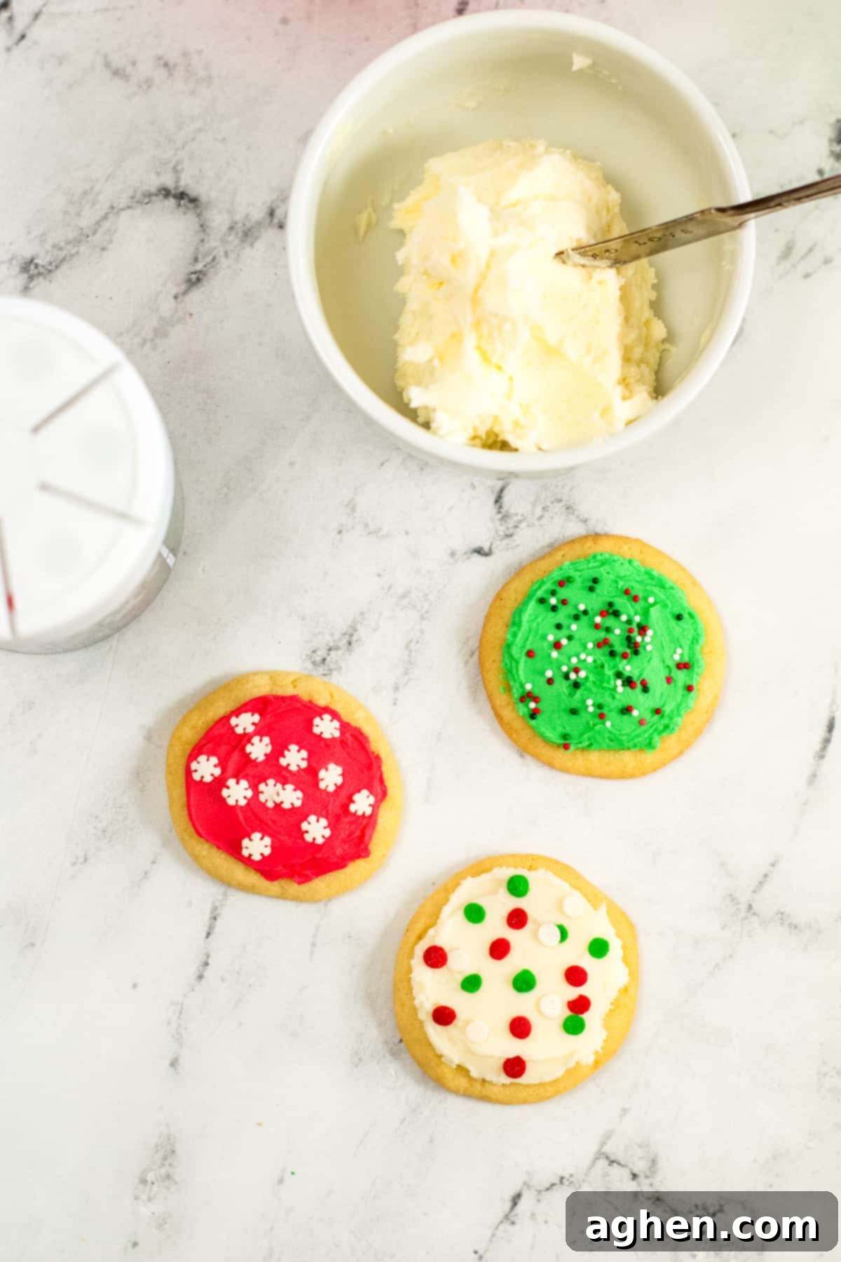 Tender Holiday Frosted Cookies 8 bowl of frosting, container of sprinkles, and 3 frosted sugar cookies