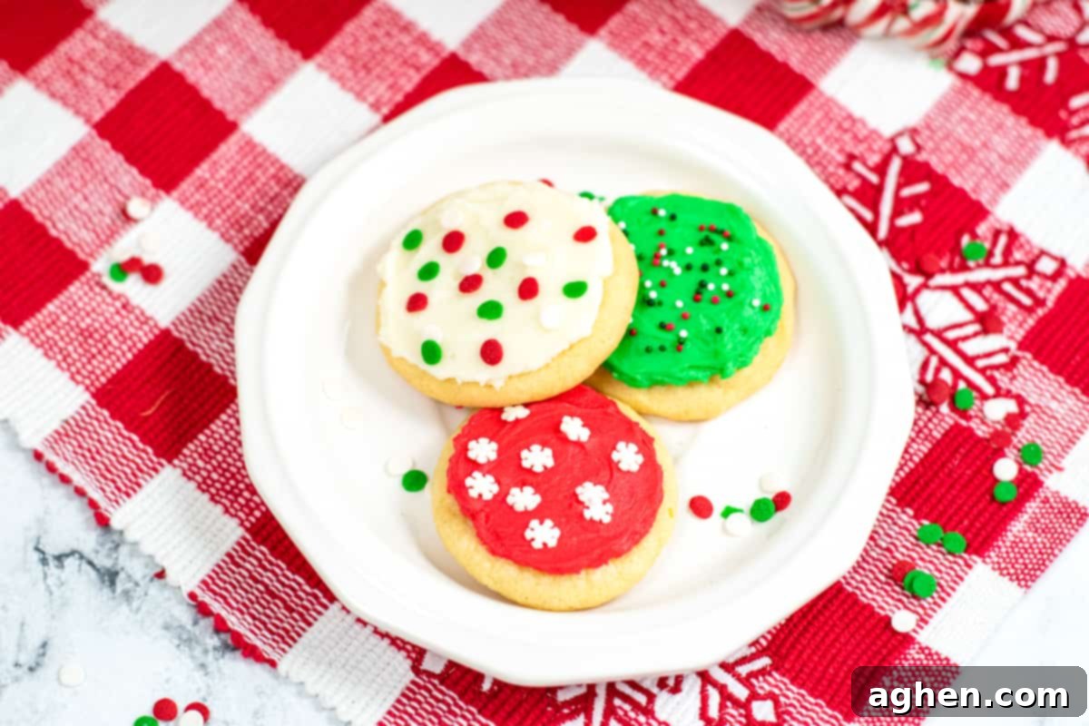 Tender Holiday Frosted Cookies 10 white dessert place with three frosted Christmas cookies, one red with white sprinkles; one green with green, white and red sprinkles; and one white with green and red confetti sprinkles.