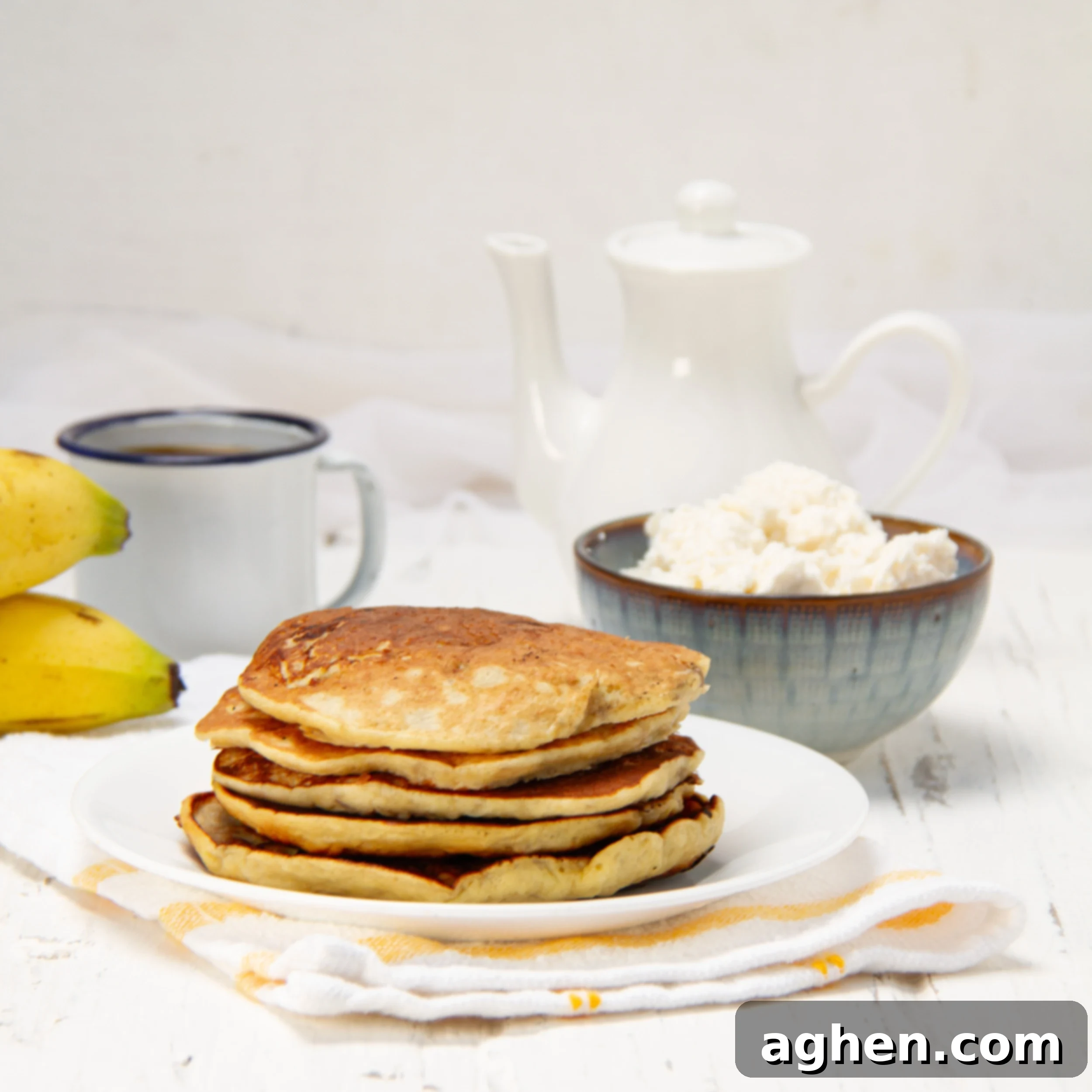 A stack of sweet and satisfying banana omelet on a plate with a bowl of cottage cheese on the side, ready to be enjoyed.