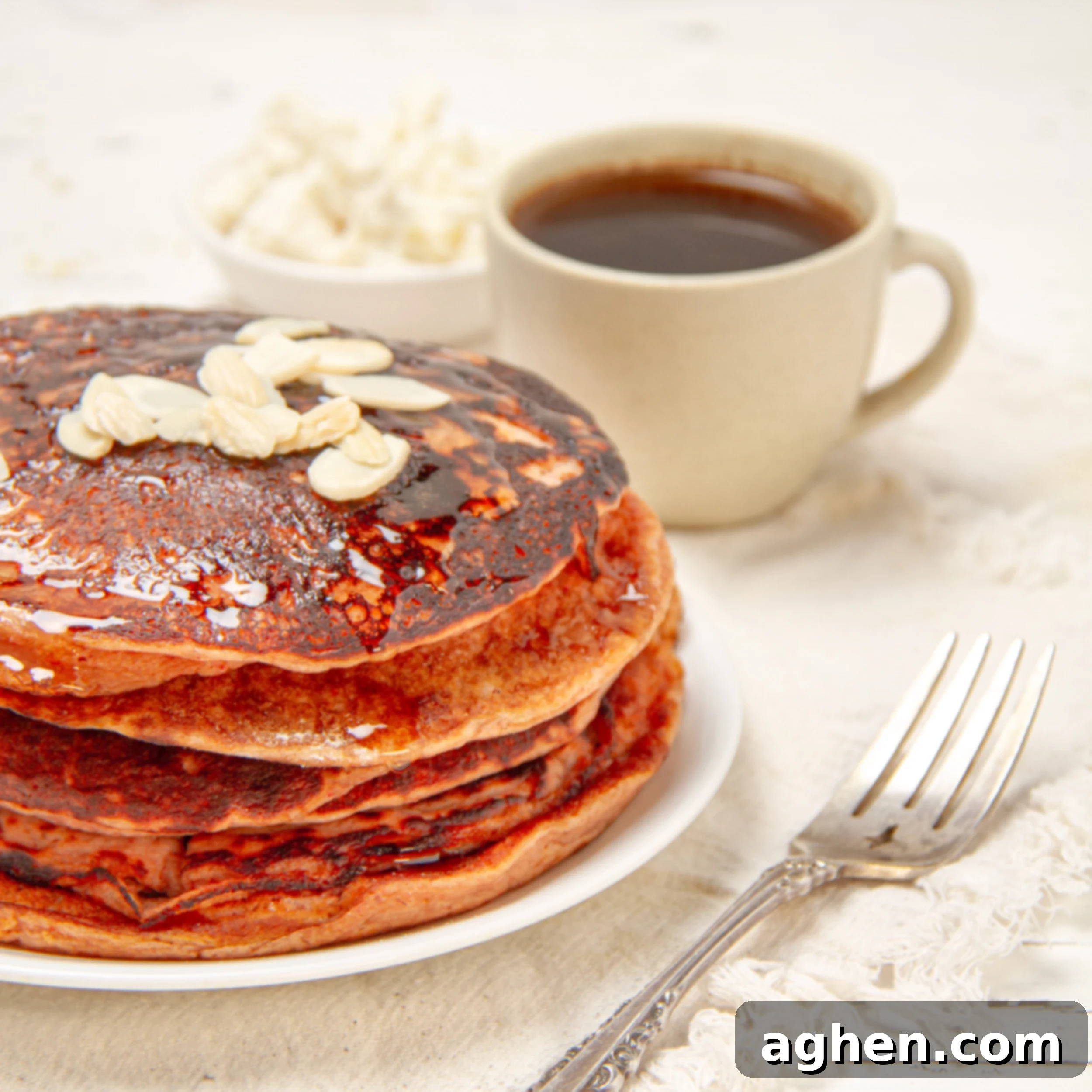 Golden Sweet Potato Pancakes 2 A stack of golden-orange Sweet Potato Pancakes on a plate with a fork and a cup of coffee on the side, inviting a cozy fall breakfast scene.