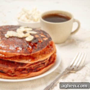 Golden Sweet Potato Pancakes 7 A stack of golden-orange Sweet Potato Pancakes on a plate with a fork and a cup of coffee on the side, ready to be enjoyed.