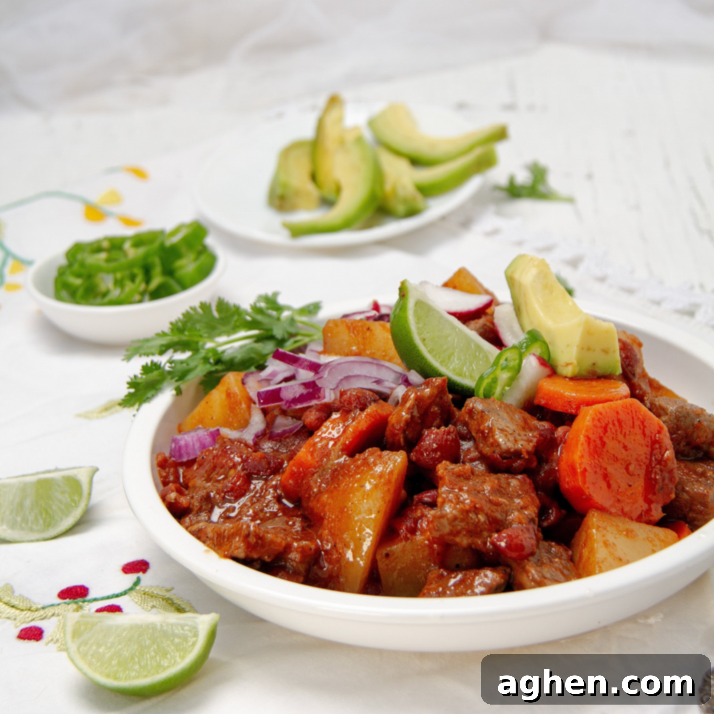 A steaming bowl of hearty Mexican Beef Stew, garnished with fresh cilantro and served with bright lime wedges.