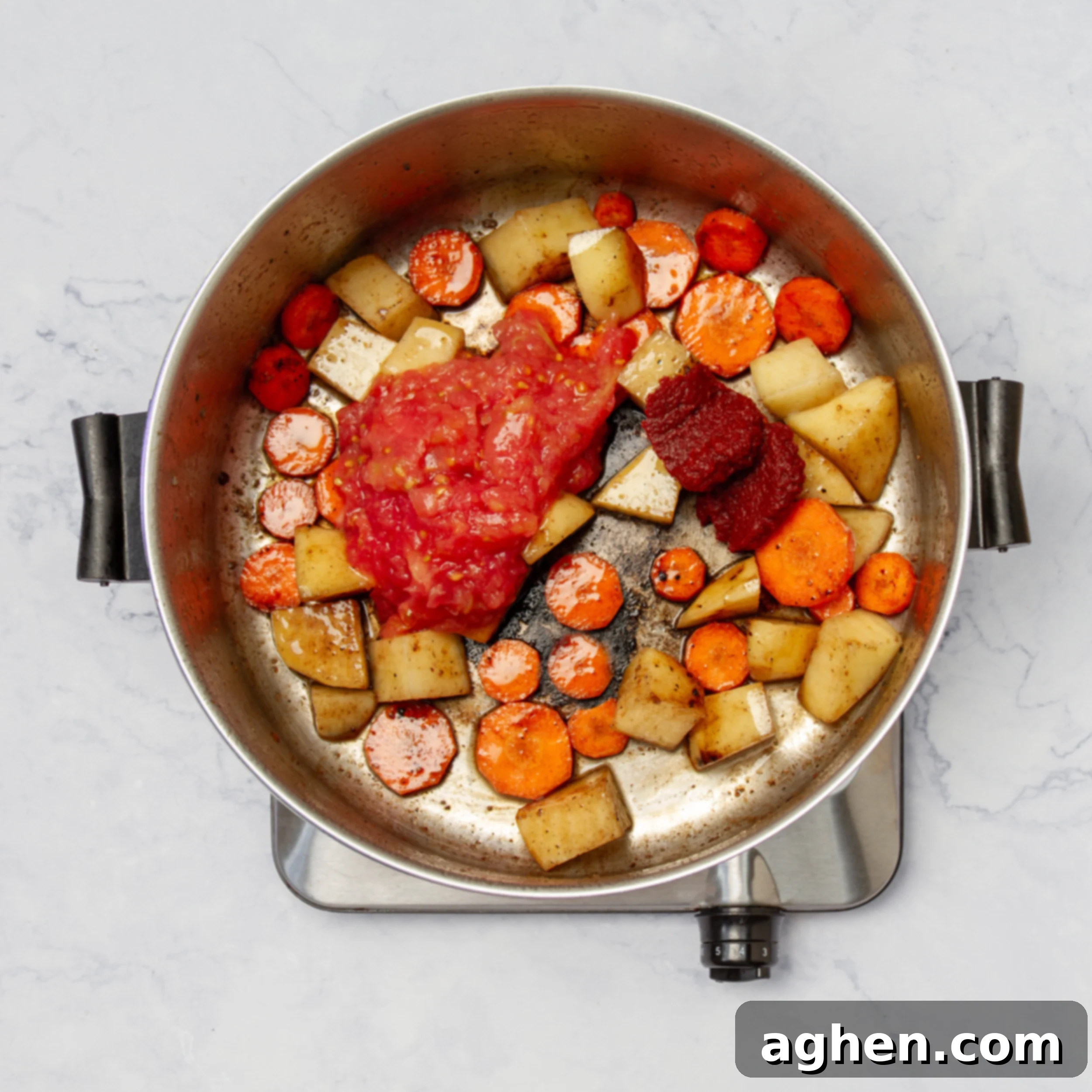 A mix of aromatic vegetables and concentrated tomato paste sautéing gently in a pan, building the flavor base for the stew.