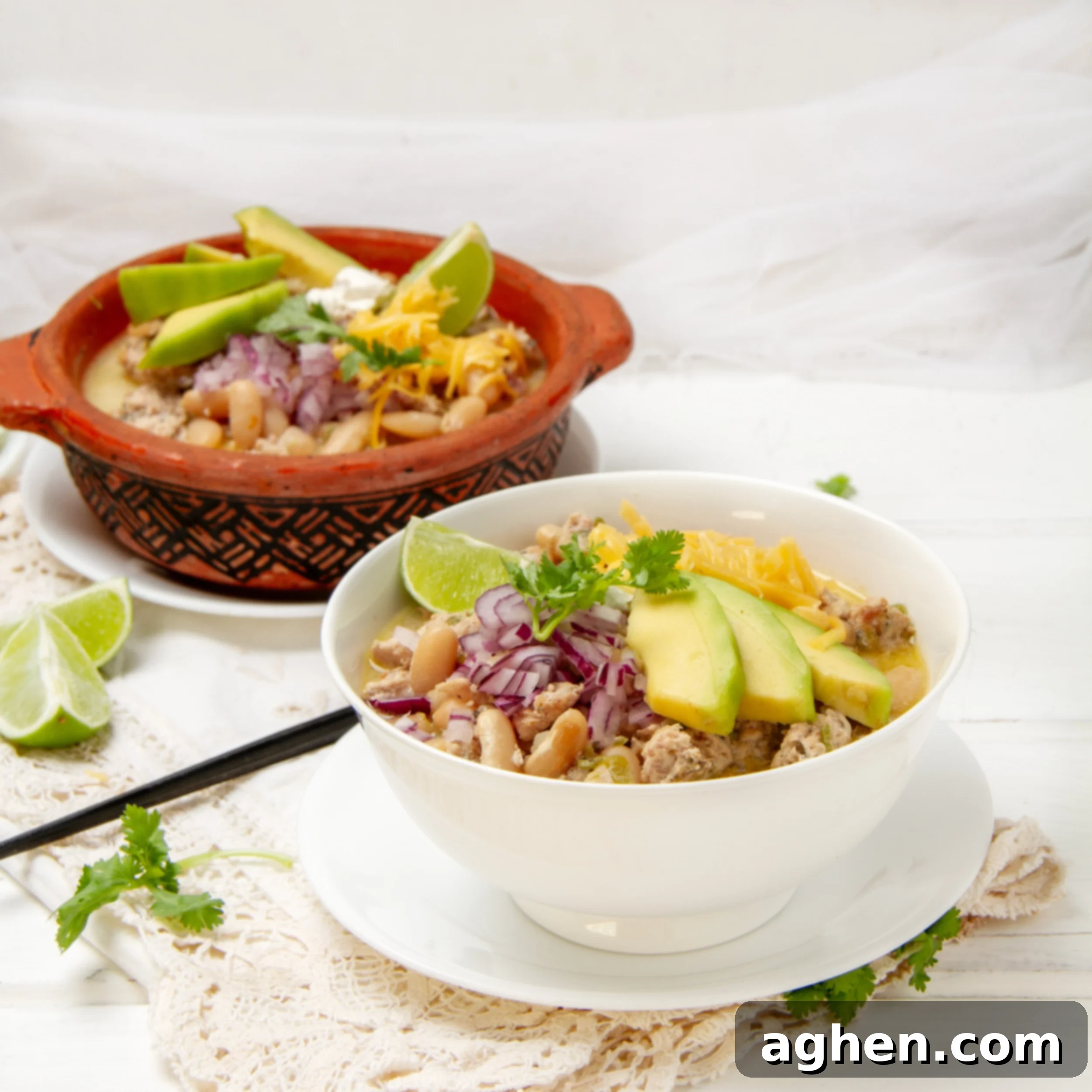 A vibrant bowl of White Turkey Chili, garnished with fresh avocado slices, chopped cilantro, and a bright lime wedge, ready to be enjoyed.