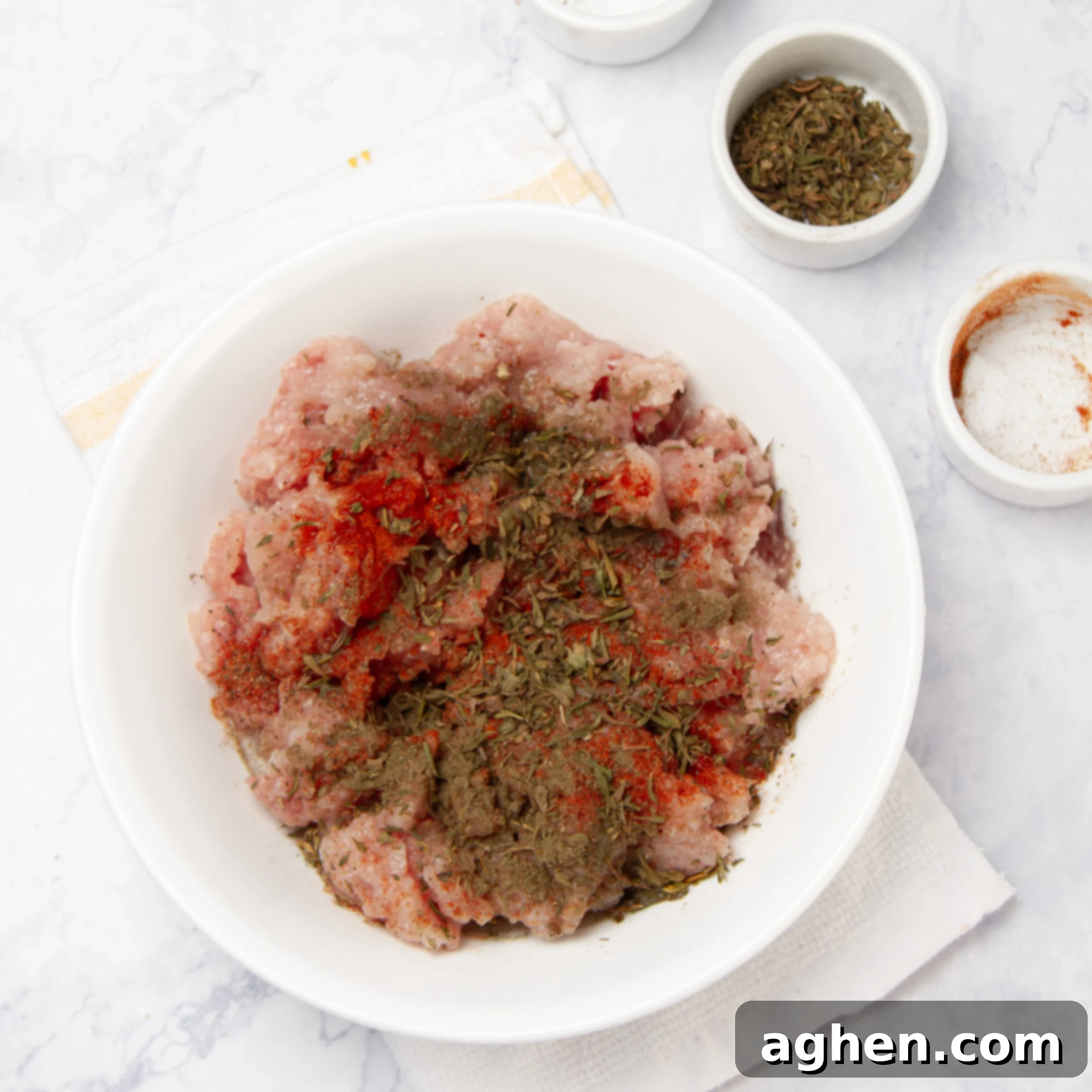 Ground turkey seasoned with various spices, including salt, cumin, and paprika, in a small bowl, ready for cooking.