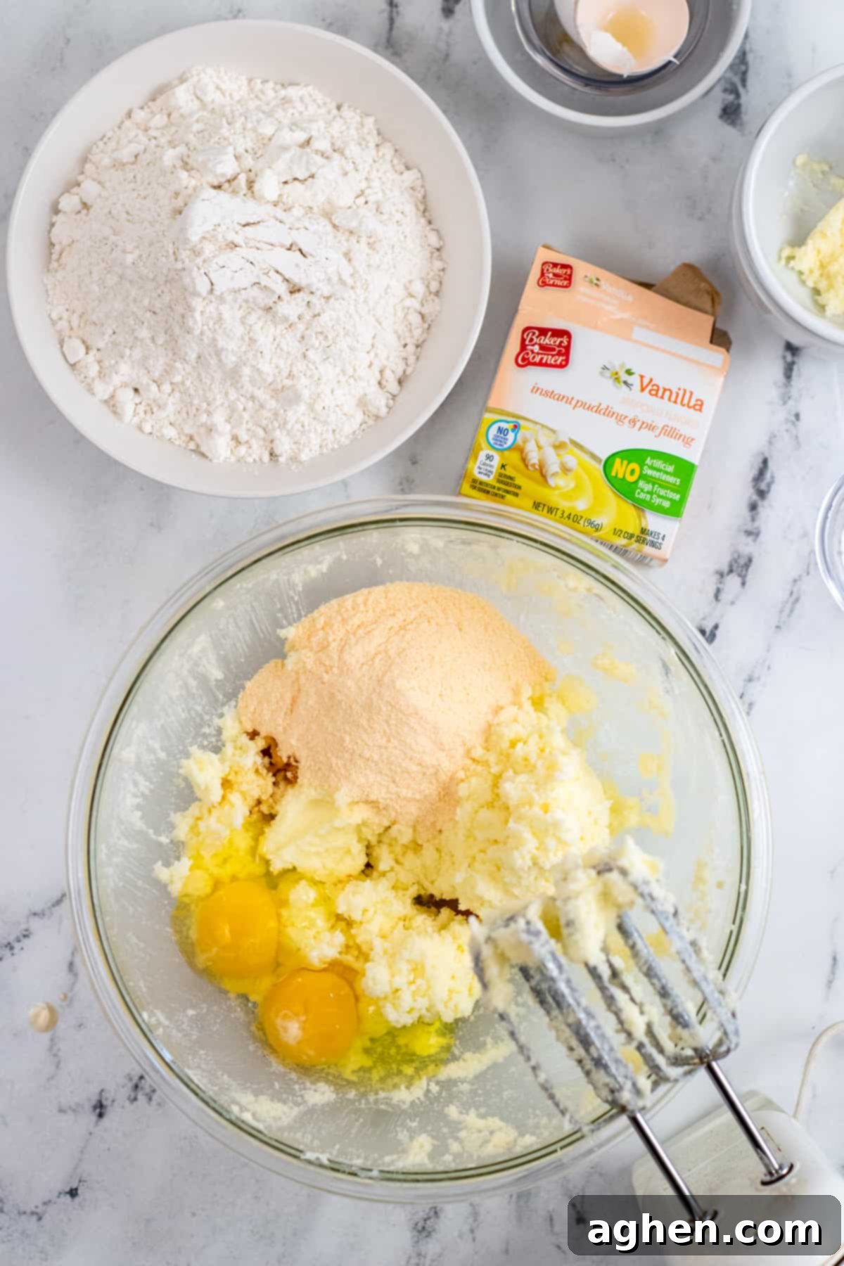 Large mixing bowl and electric mixer with creamed sugar and butter and pudding mix, egg, and vanilla extract added.