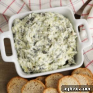 creamy crockpot spinach and artichoke dip in white bowl served with small pieces of bread for dipping