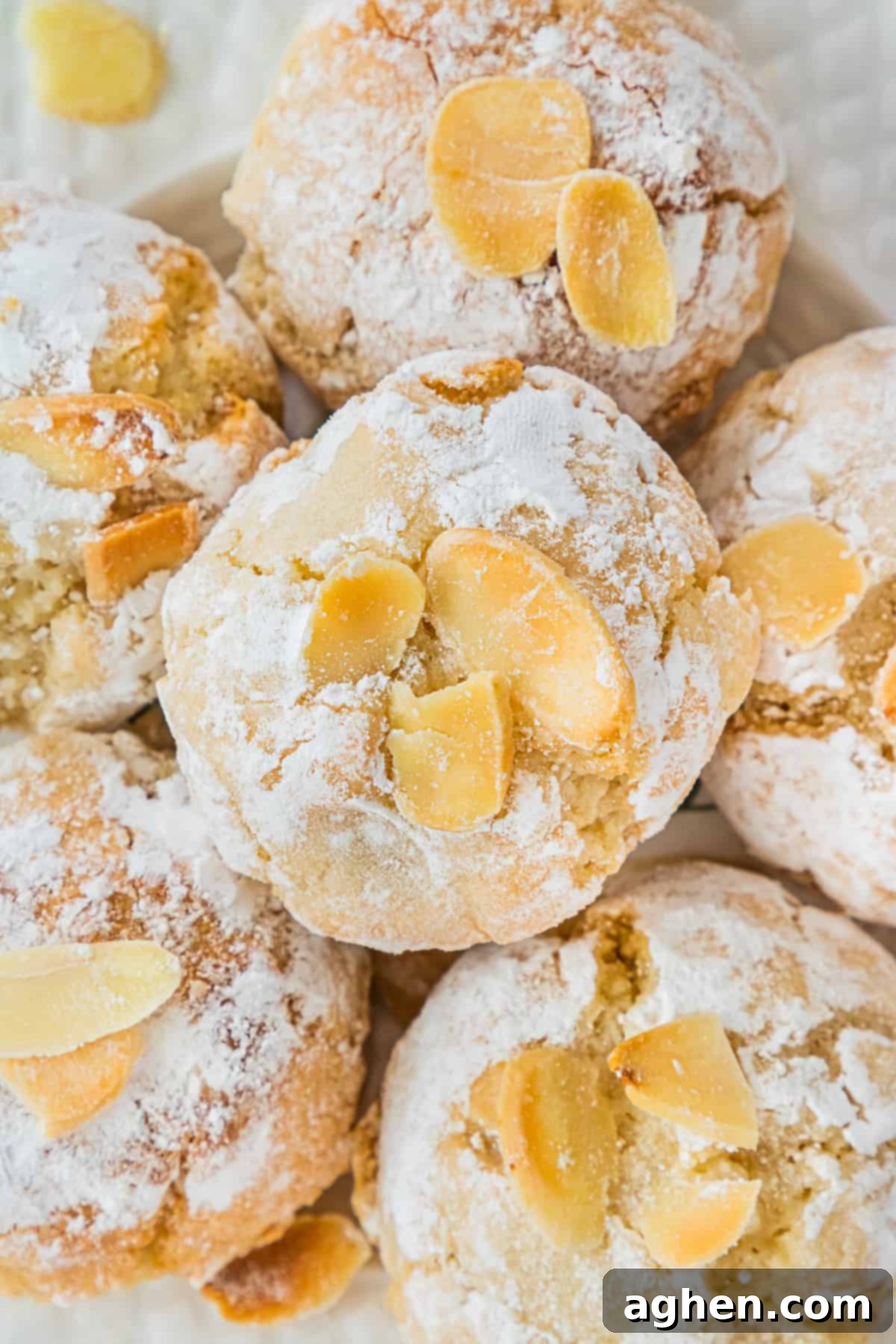 Italian Amaretti Cookies rolled in confectioners sugar and topped with flaked almonds