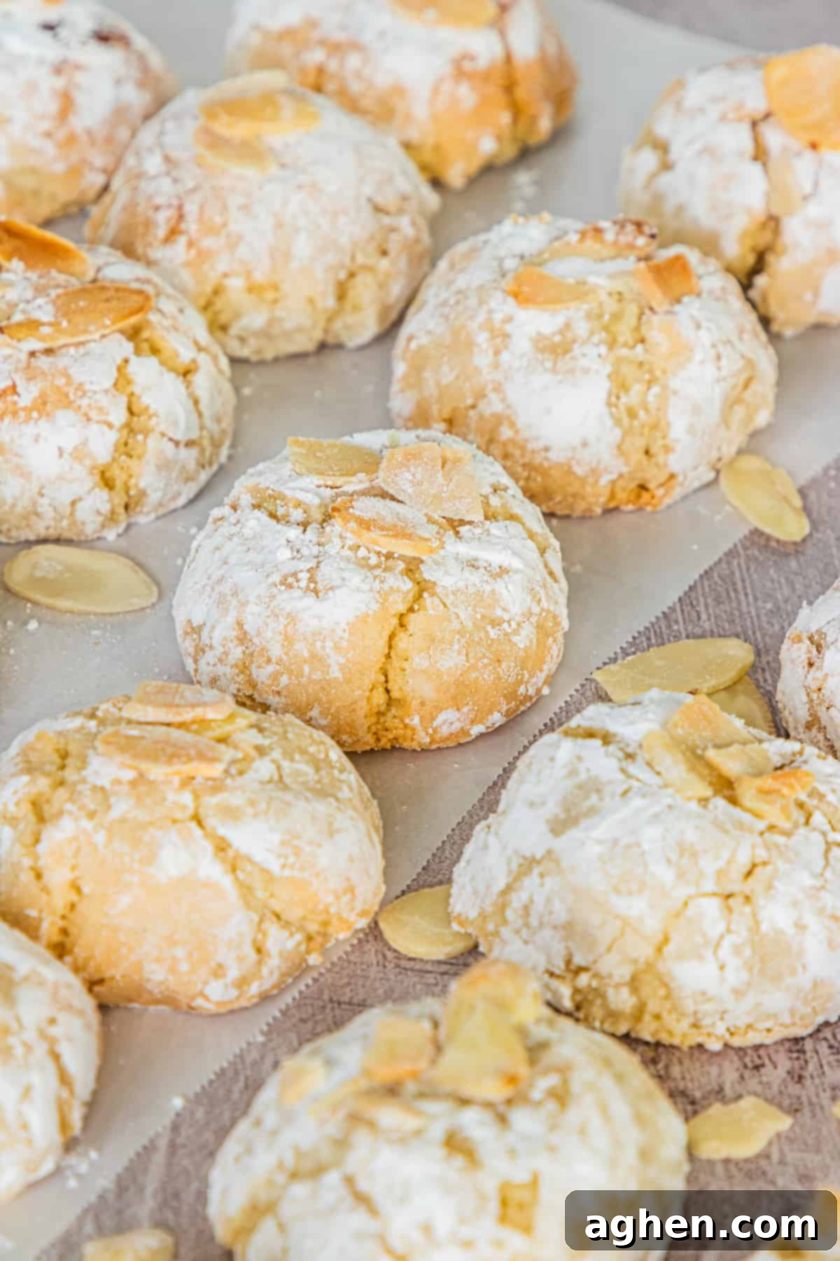 Soft Italian Amaretti Cookies with flaked almonds lined up neatly on parchment paper