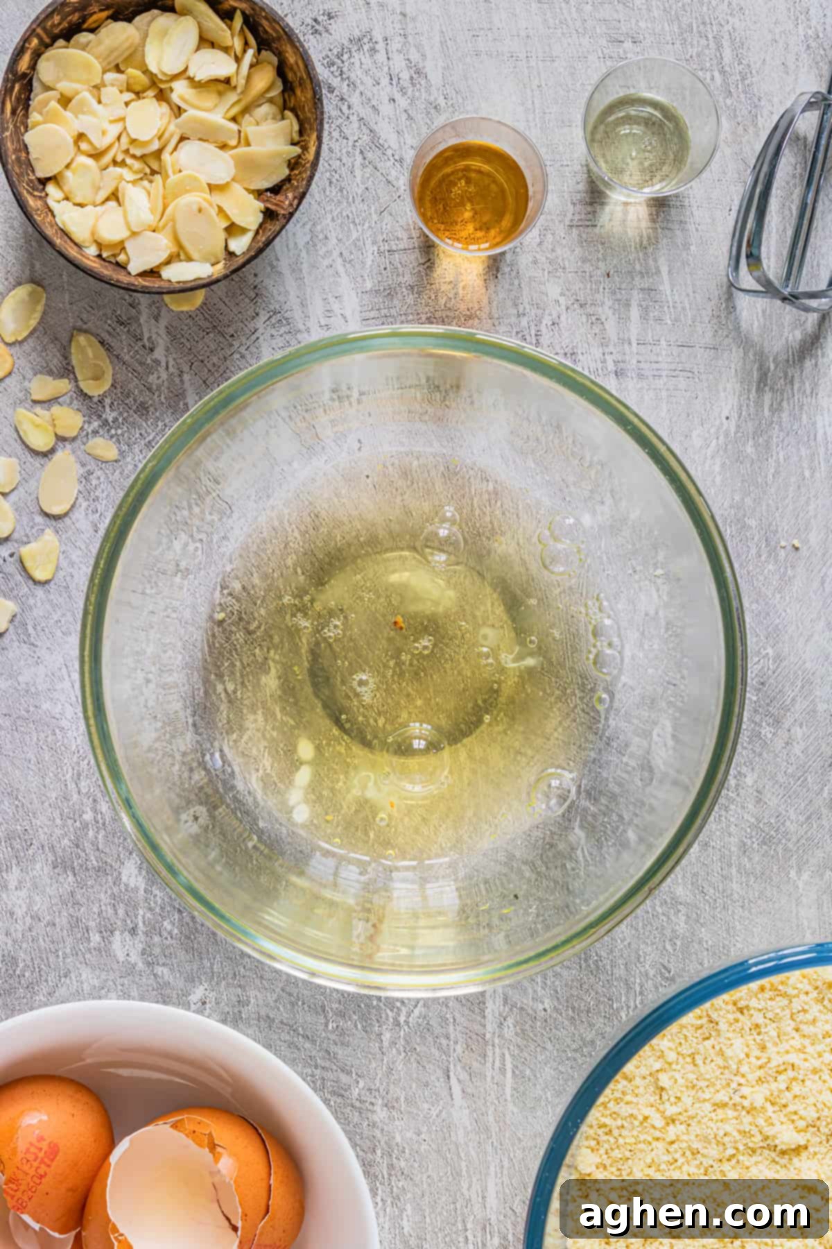 egg whites in a glass bowl with electronic mixer next to it 