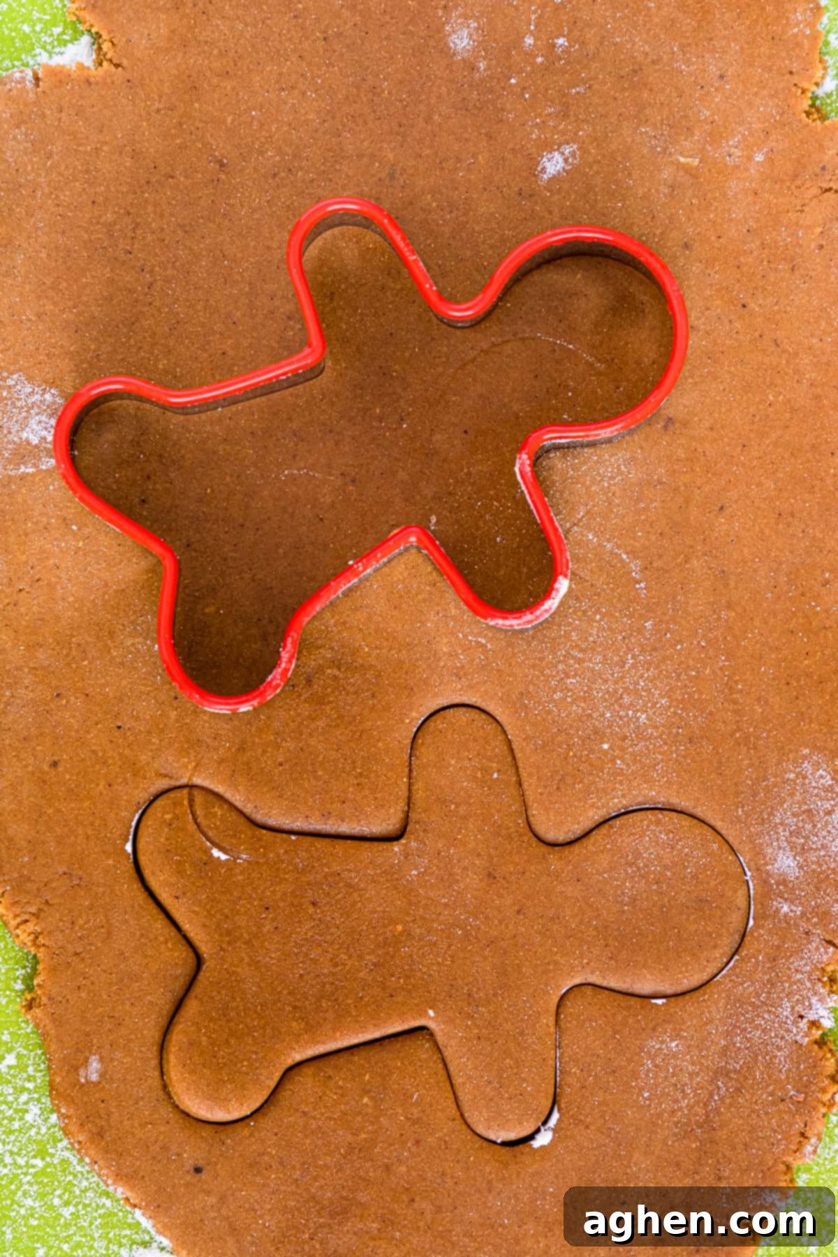 man shaped cookie cutter cutting gingerbread cookie dough