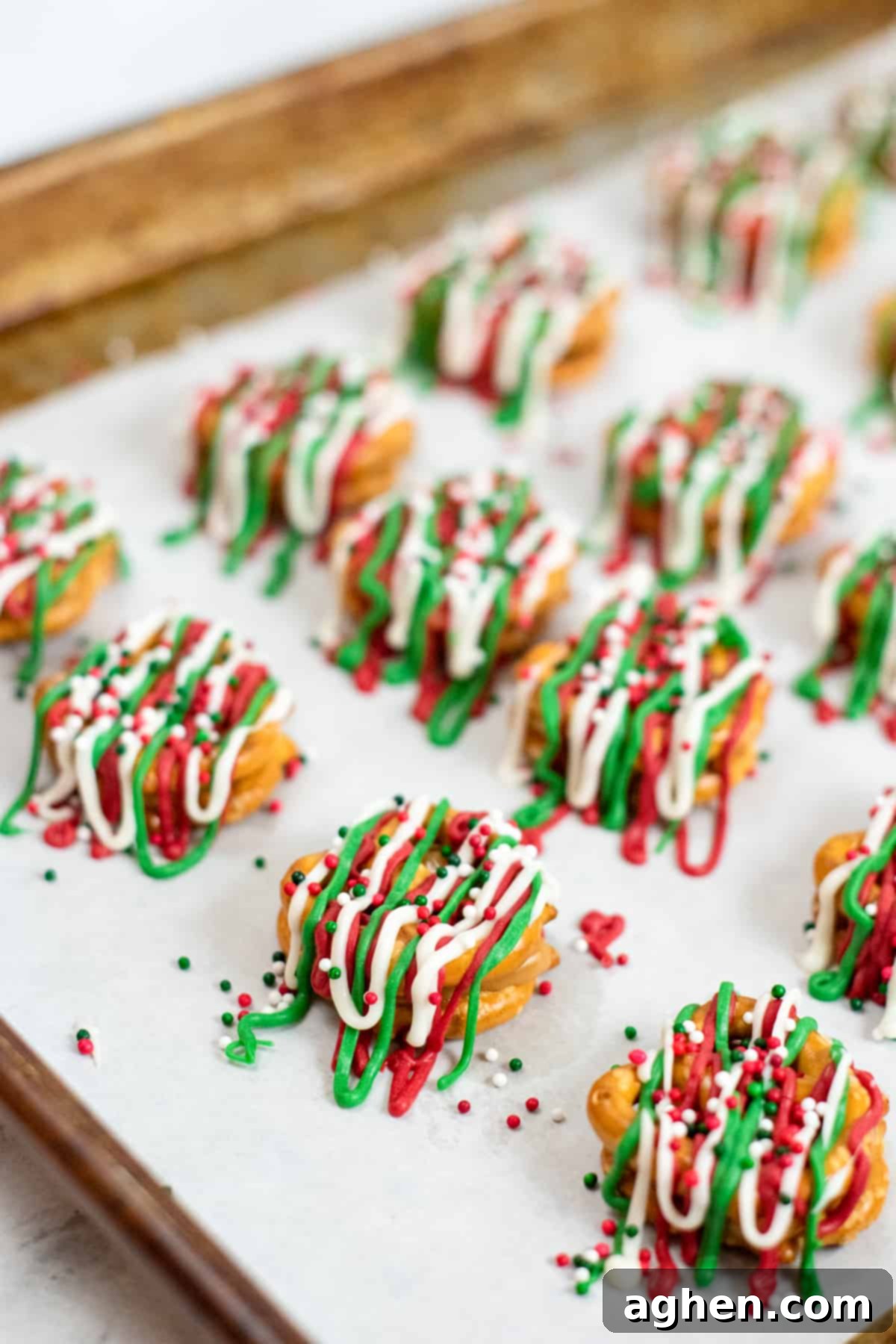 Pretzel Bites on parchment-lined baking sheet topped with red, green and white candy drizzles and christmas sprinkles