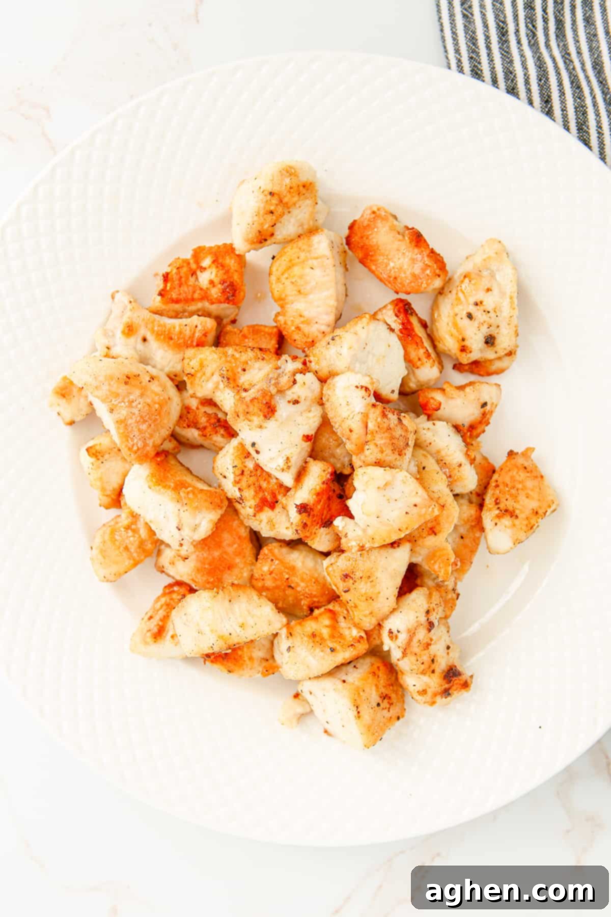Golden brown pan-fried chicken pieces resting on a plate after cooking.
