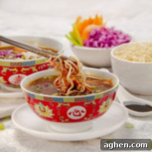 Manchow Soup: A Flavor Explosion 7 Thick and chunky Asian-inspired Manchow Soup in a bowl with noodles held up with chopsticks.