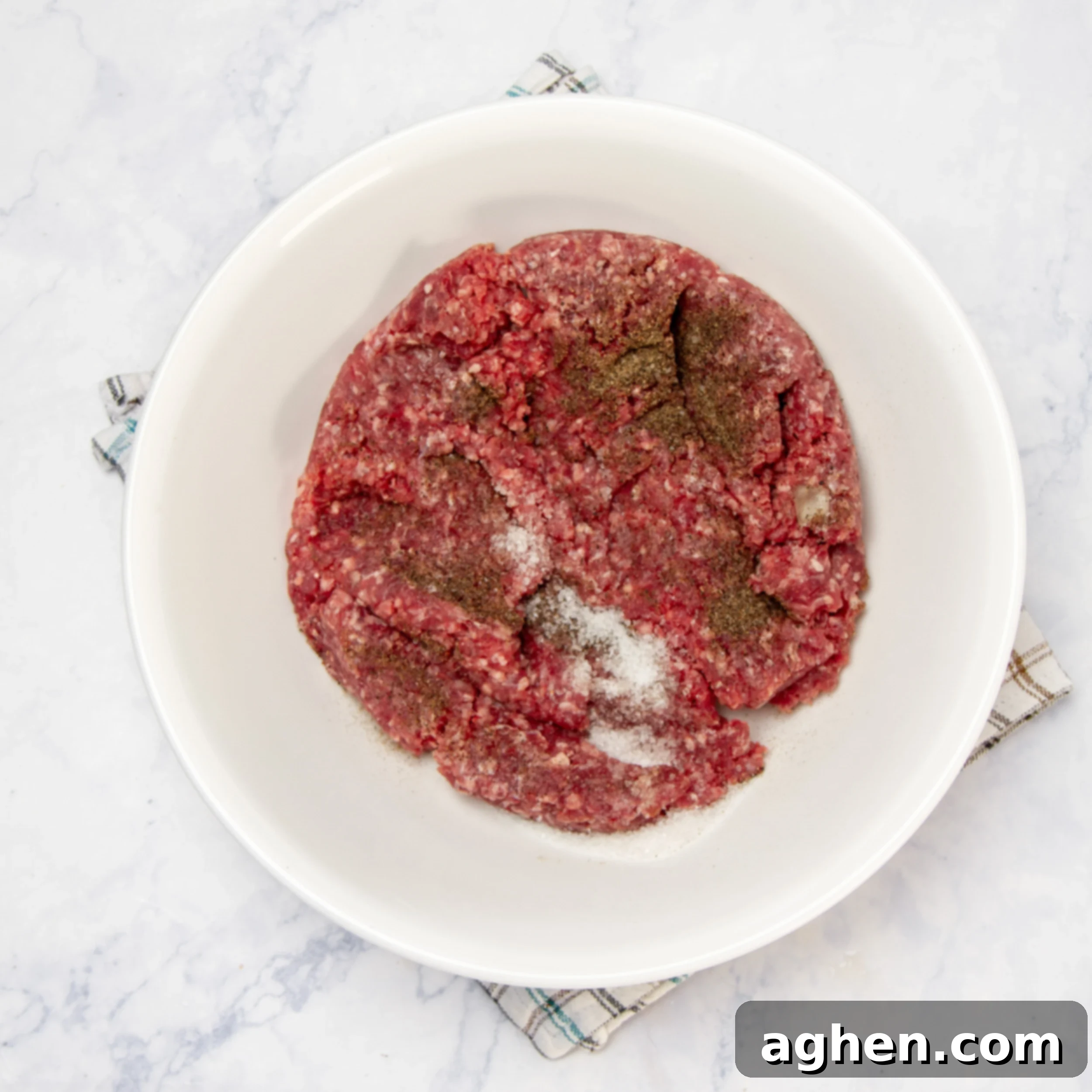 Seasoning the ground beef in a small bowl with salt and pepper.