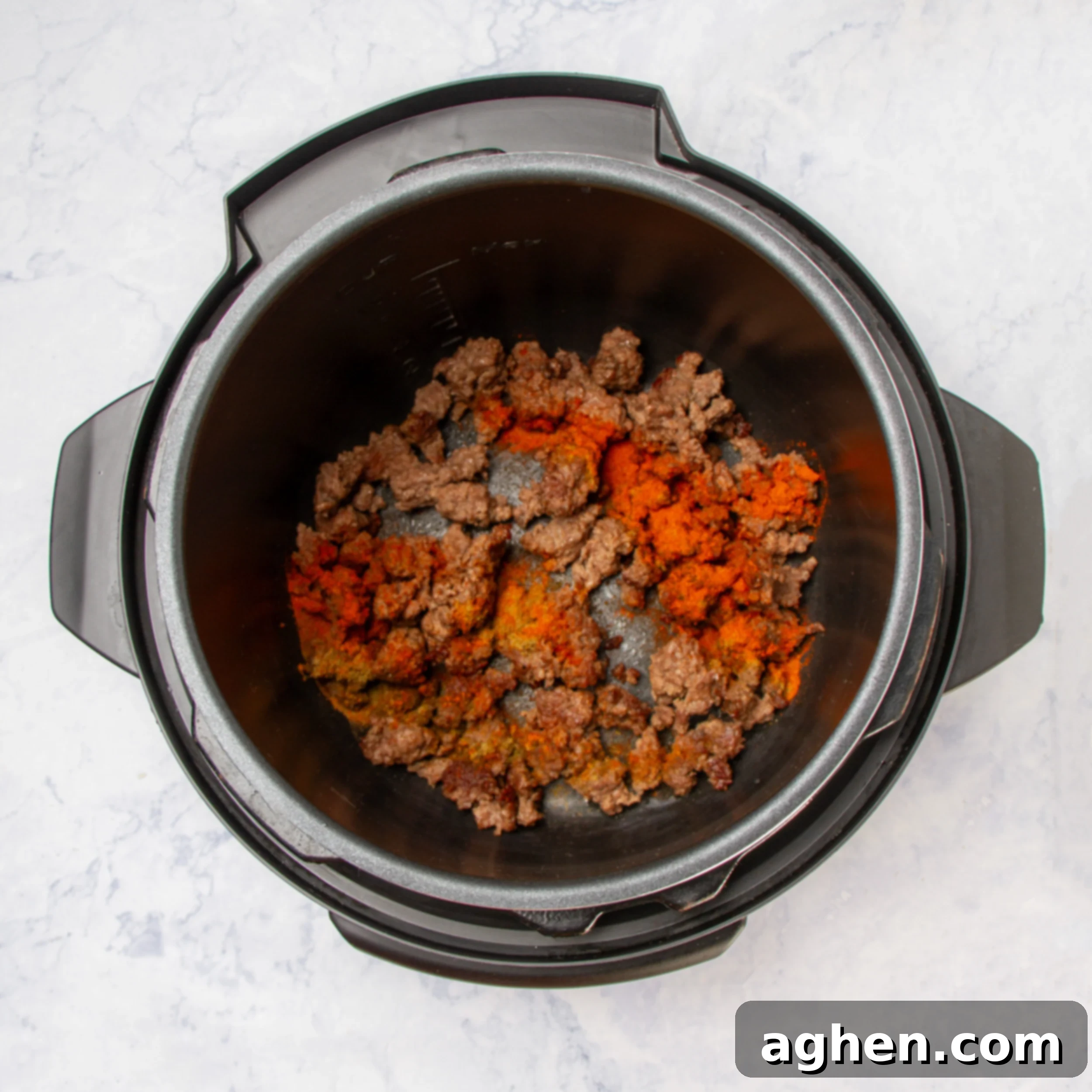 Sautéing the ground beef in the Instant Pot, breaking it apart as it cooks.