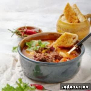 Hearty and historic Cowboy Soup in a bowl with fresh toppings.