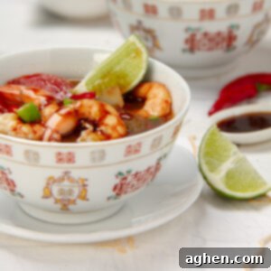 Tom Yum Soup 9 Thai classic Tom Yum Soup with shrimp in a bowl, garnished with a fresh lime wedge.