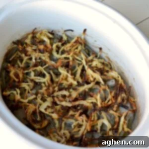 Close-up of the finished slow cooker green bean casserole, topped with a generous amount of homemade crispy onions.