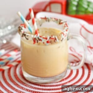 Gingerbread cocktail with vodka and kahlua in glass mug with sprinkles on rim and two paper straws. Christmas decor is in the background.
