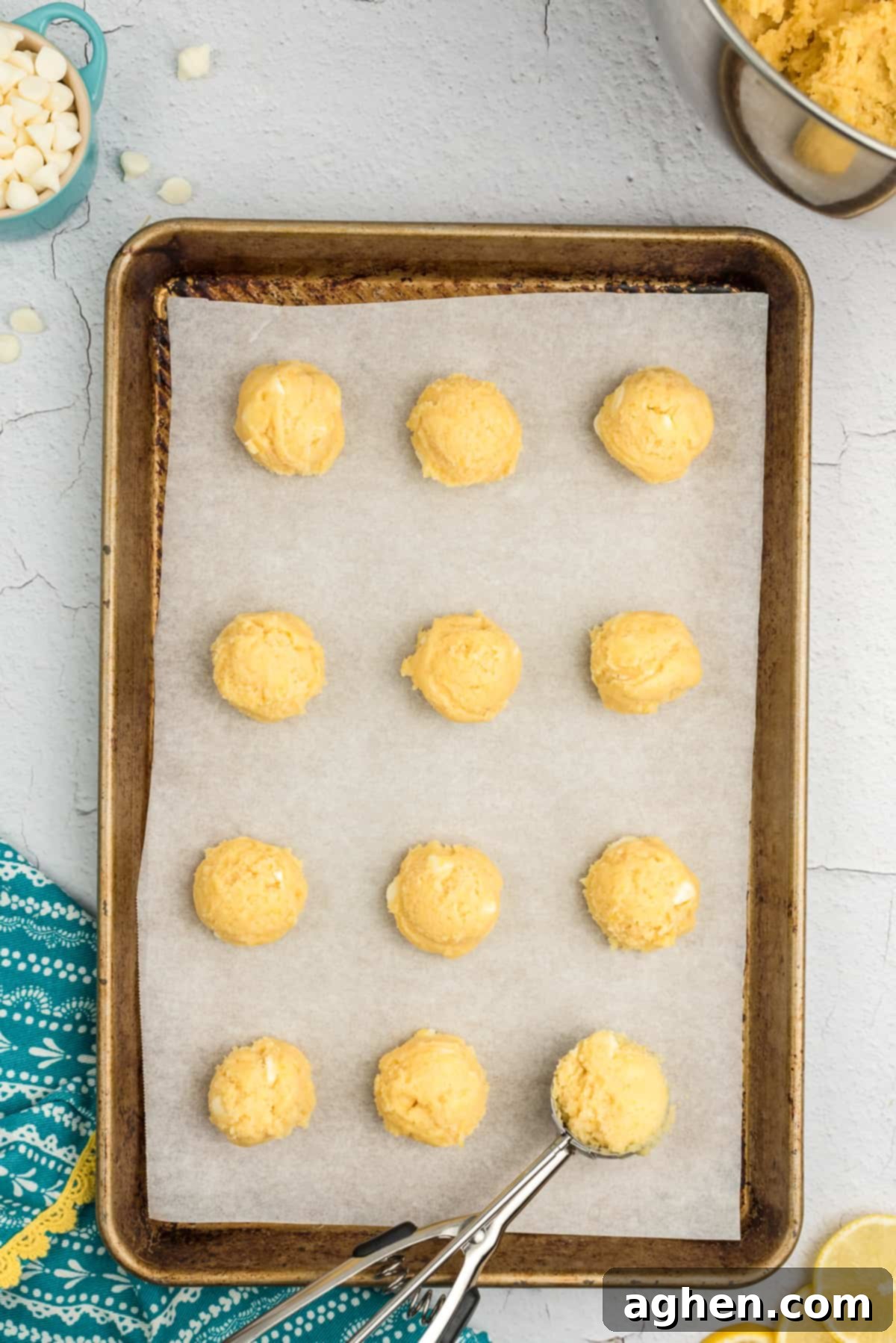 Scooped lemon cookie dough balls evenly spaced on a parchment-lined baking sheet.