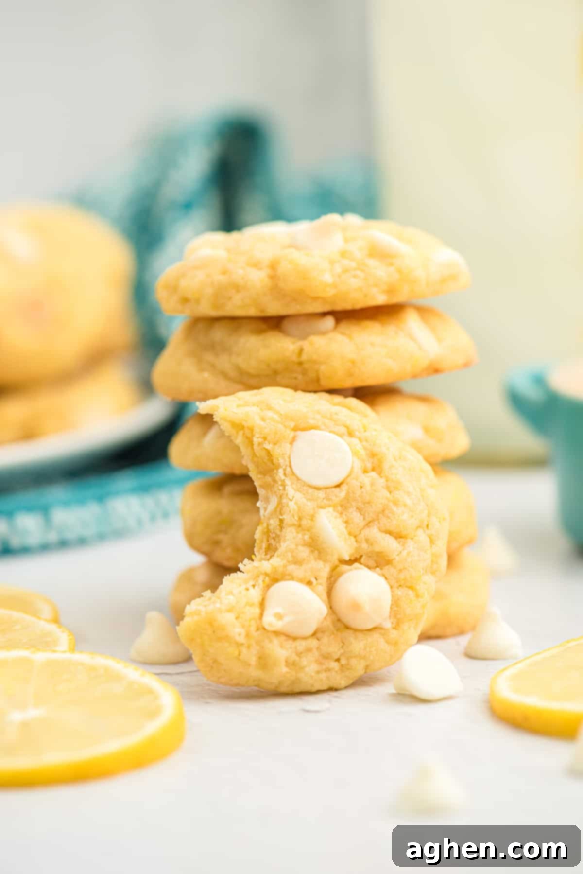 Stack of soft lemon cookies with white chocolate chips, one with a bite taken out, highlighting the tender interior.