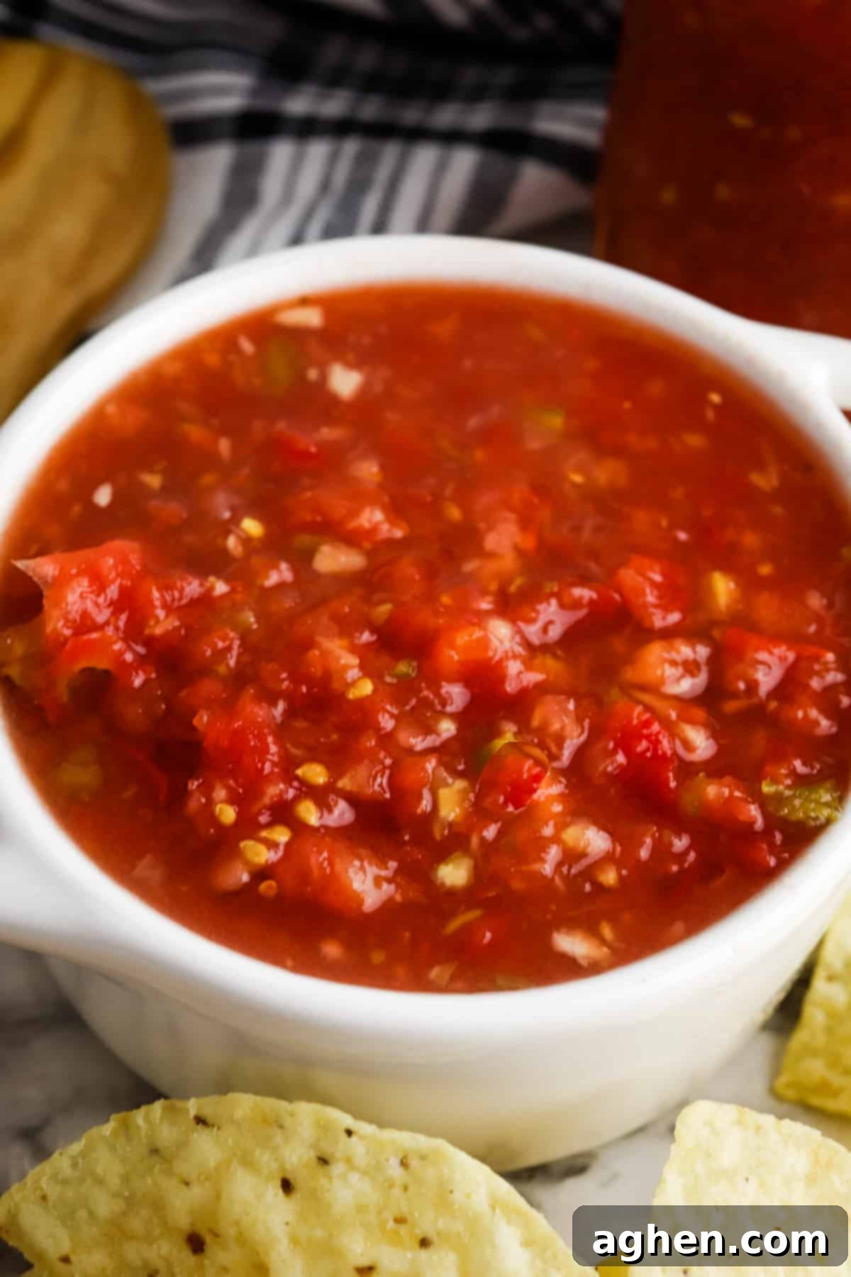 Rotel Salsa in a white serving bowl with tortilla chips and a cloth napkin next to it, ready to eat