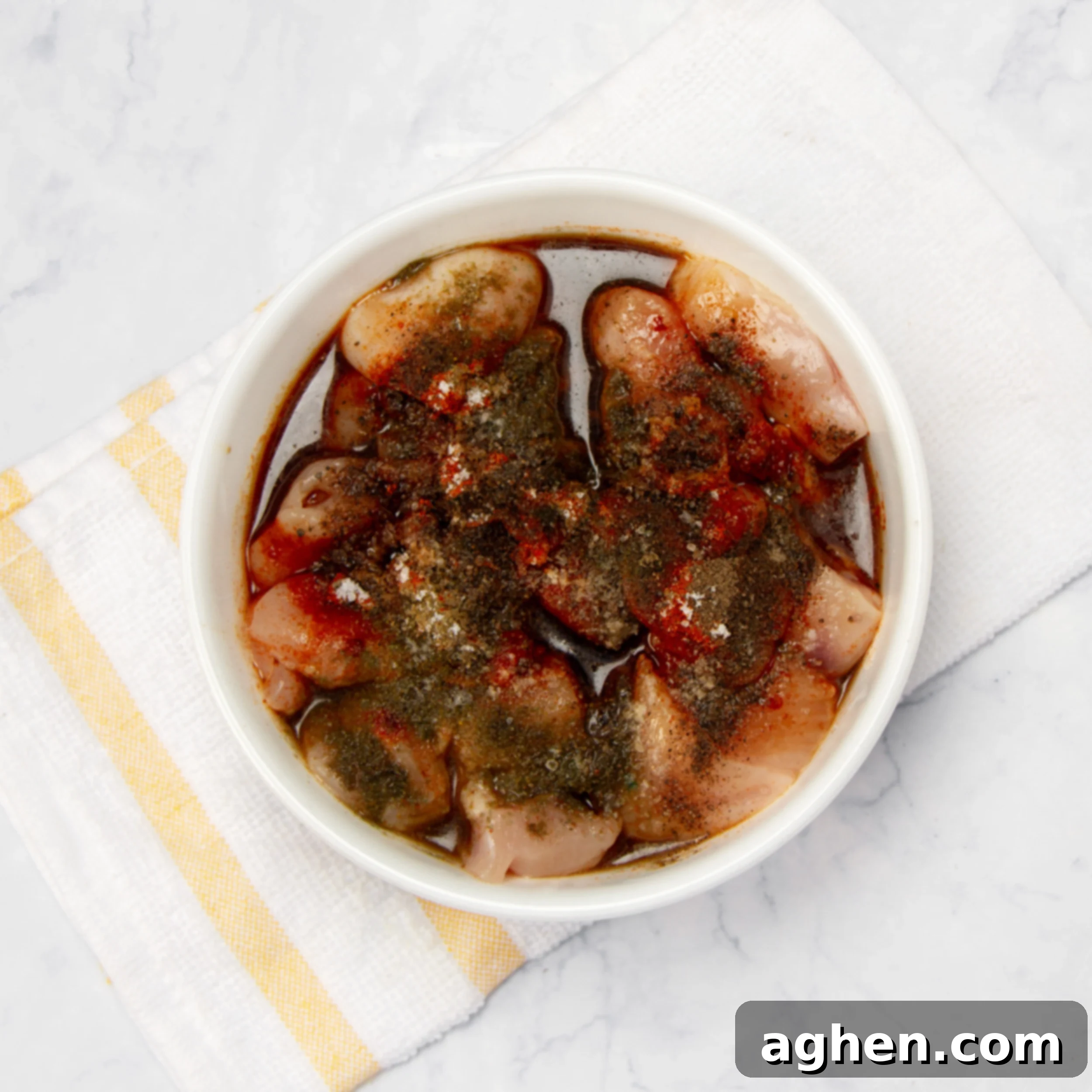 Raw chicken marinating in a small bowl. 