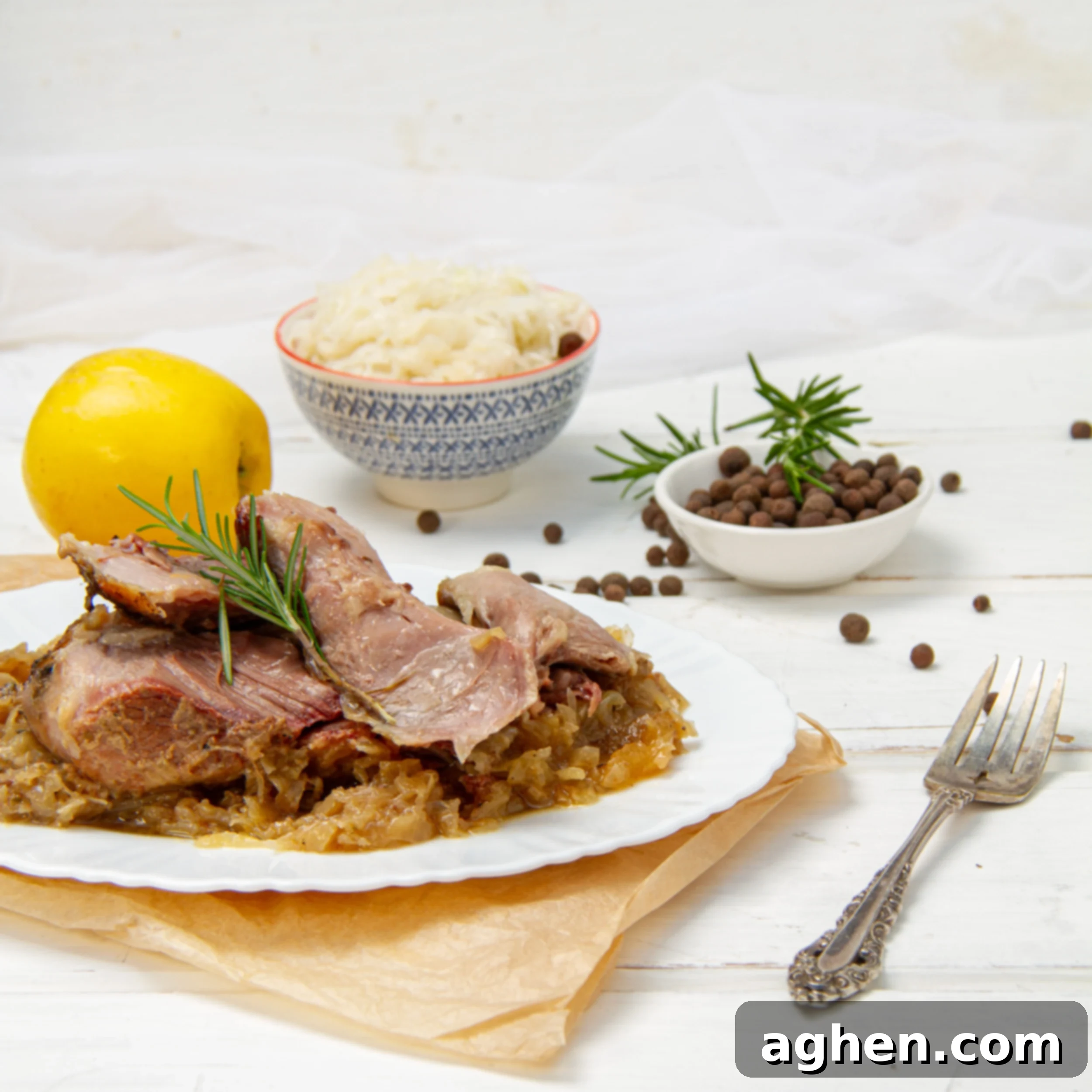 Tender pork and sauerkraut on a plate with a whole lemon and a fork on the side.