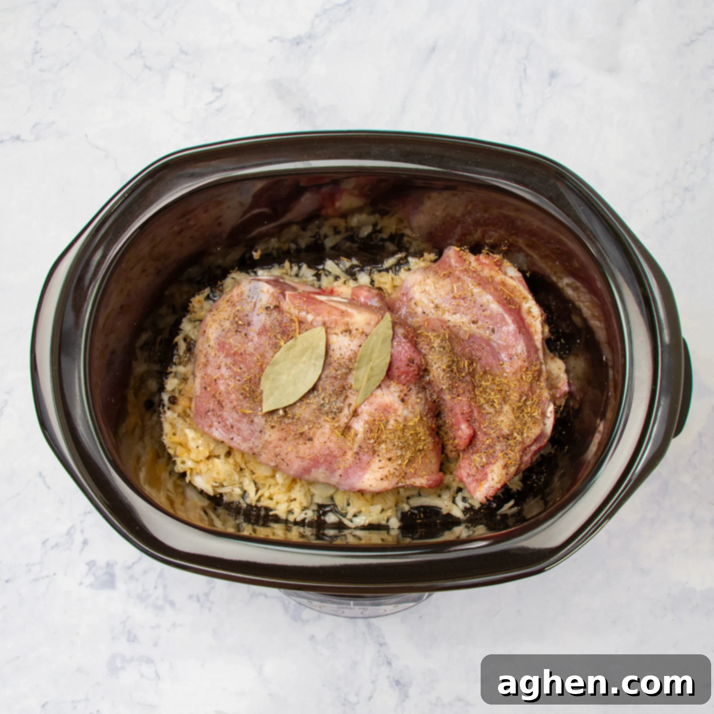 Sauerkraut and meat in the slow cooker with bay leaves and seasonings. 