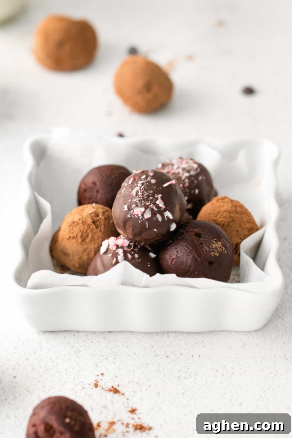dark chocolate truffles in serving plate, some rolled in cocoa powder, some plain, and some coated in chocolate topped with crushed peppermint candy